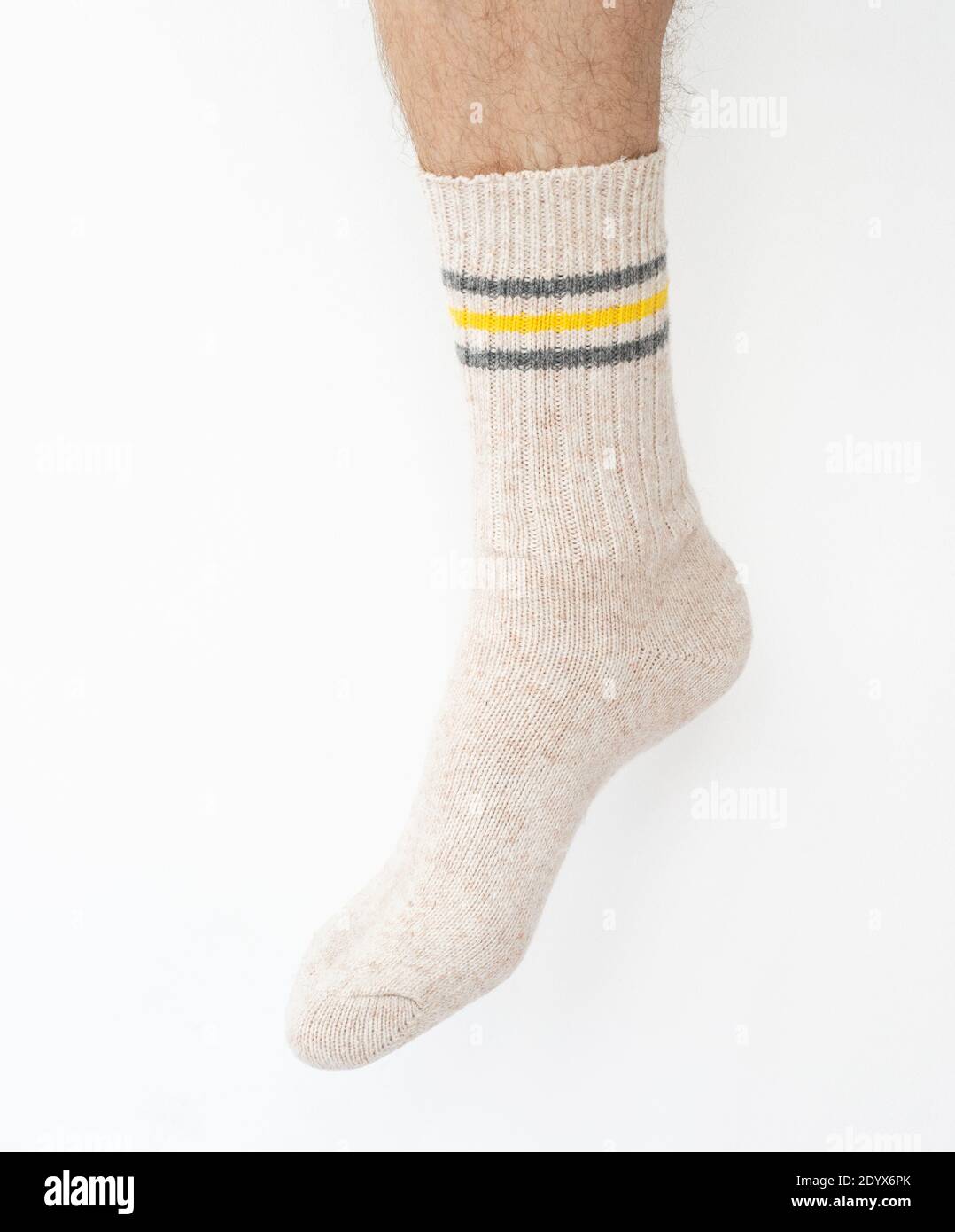 Calza beige in lana sulla gamba di un uomo su una luce sfondo Foto Stock