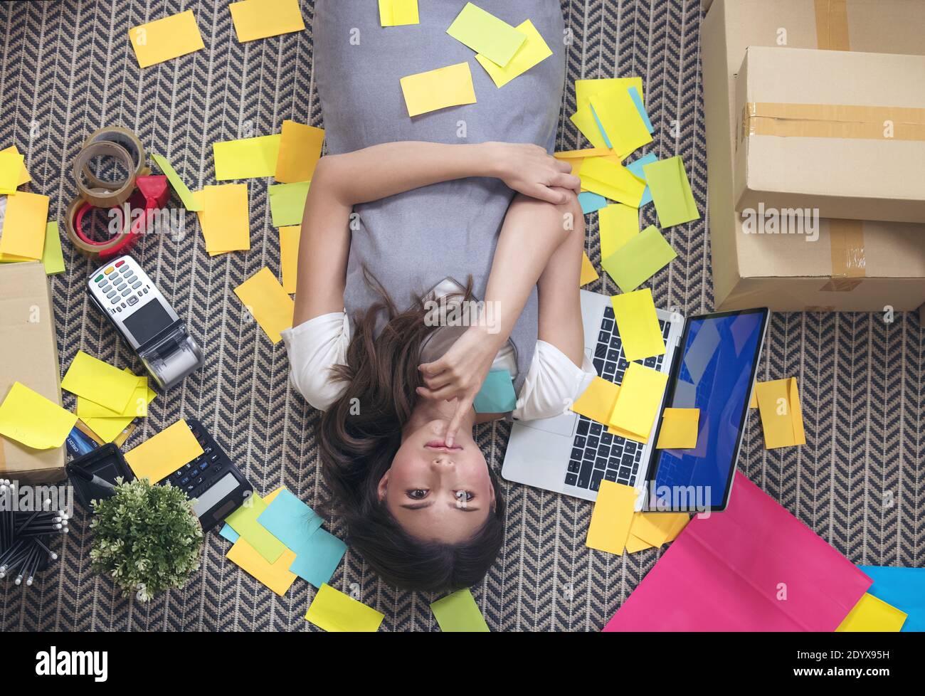 Freelancer esausto che prende un pisolino nel sonno sul pavimento all'ufficio domestico. Donna attraente a casa Foto Stock