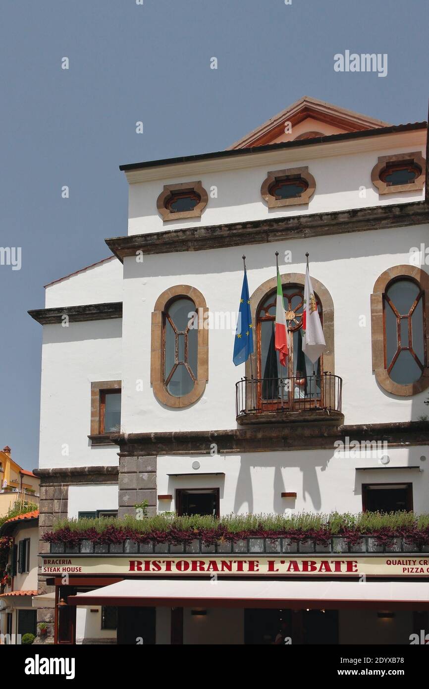 Sorrento - 9 luglio 2019: Facciata di edificio con balcone e bandiere sulla basilica di Sant'Antonio Foto Stock