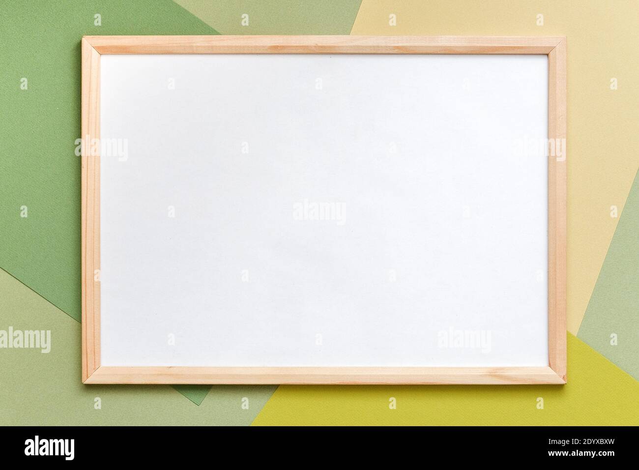 Cornice in legno bianco su sfondo di carta verde geometrico. Spazio di copia, mockup per il vostro disegno, testo. Foto Stock