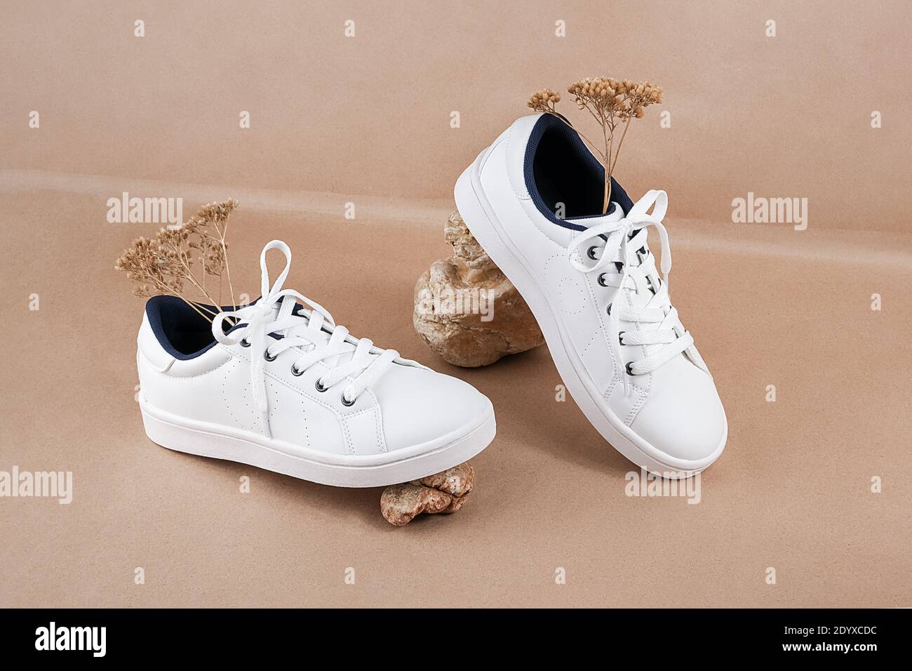 Concetto etico di scarpe vegan. Un paio di sneaker bianche con fiori secchi  sulle pietre contro uno sfondo di carta da artigianato beige neutro Foto  stock - Alamy