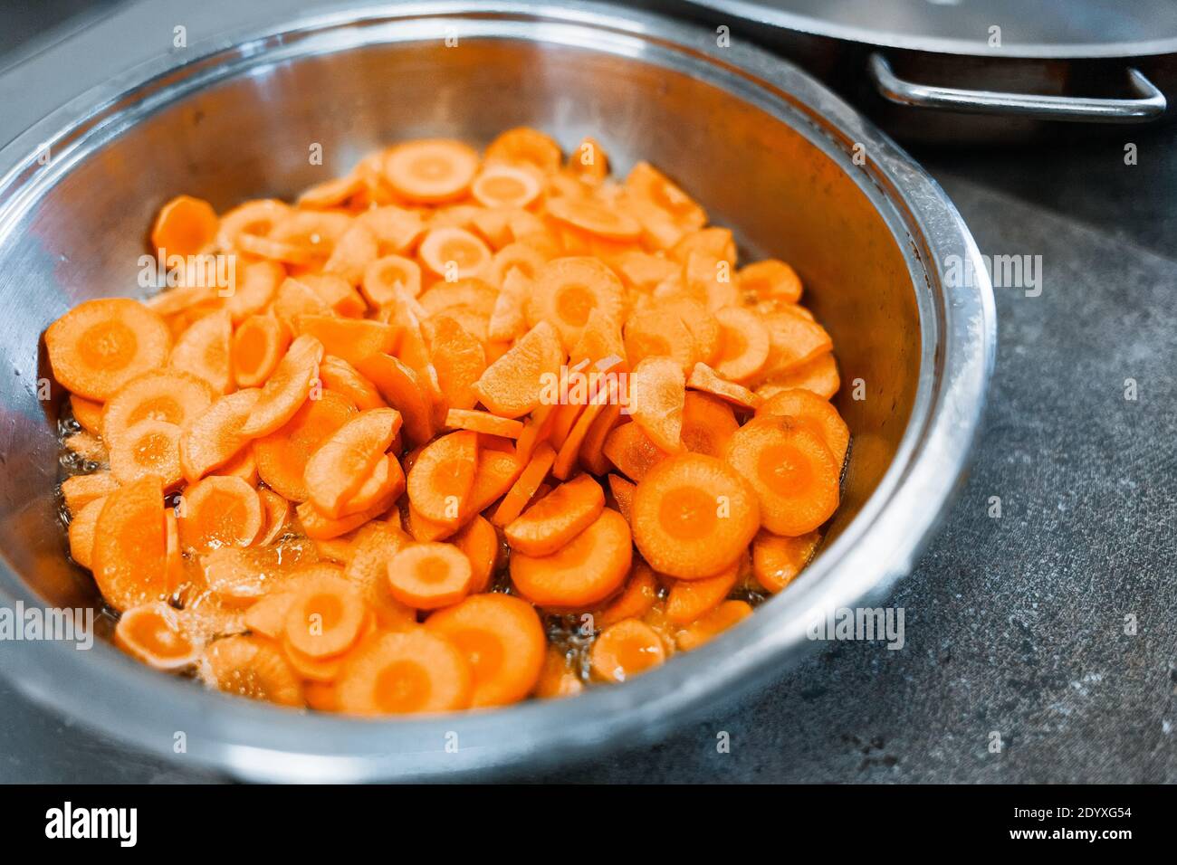 Cucina nella sala da pranzo. Pezzi di carote a fette sono nella padella. Foto Stock