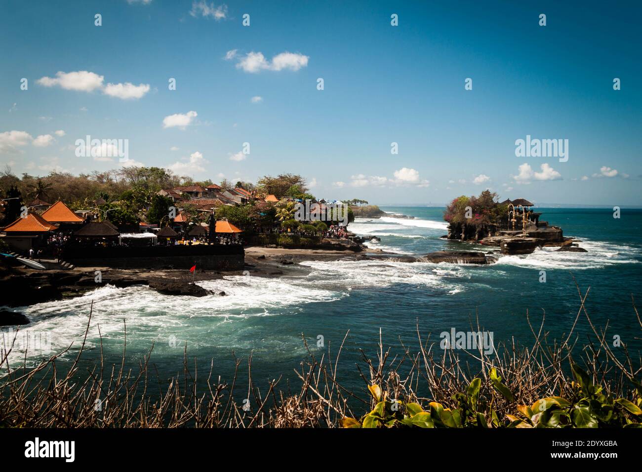 Tempio Tanah Lot nell'oceano ondulato e nei ristoranti sulla costa Foto Stock
