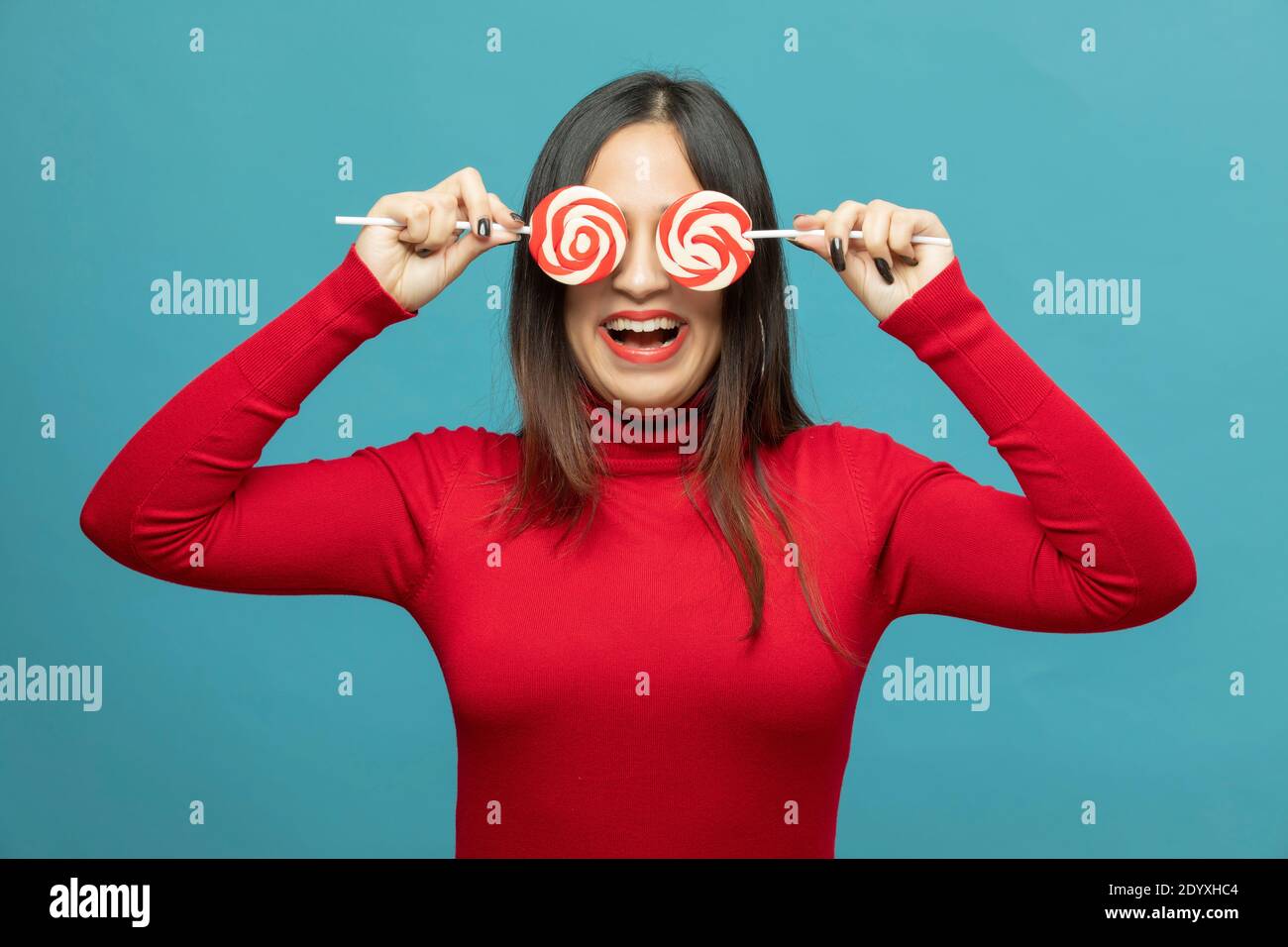 giovane donna che ricopre l'occhio con lollipop e sorridente Foto Stock