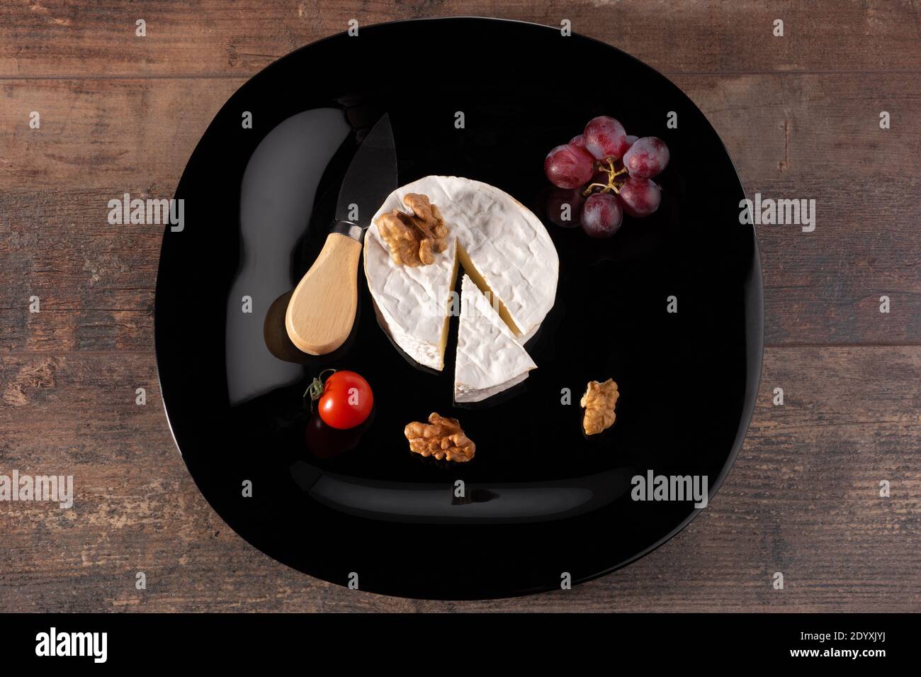 Delizioso formaggio brie su piatto nero. Tavola rustica in legno. Tipo Brie di formaggio. Camembert. Formaggio Brie fresco e una fetta su tavola di pietra. Italiano, Fren Foto Stock