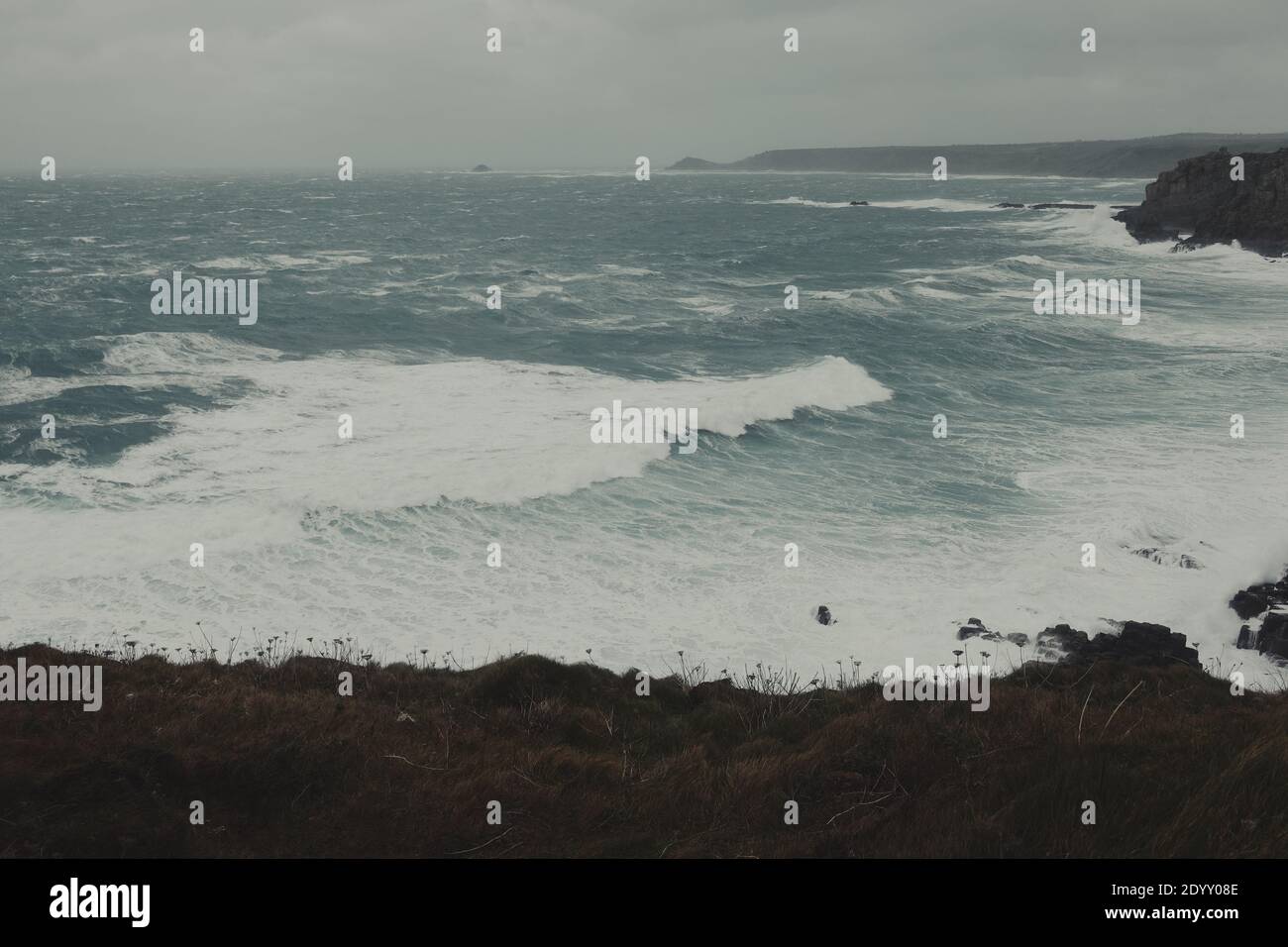Mari burrasdi e onde dell'oceano Atlantico che si infrangono sulle rocce a Lands End Cornwall, Regno Unito dopo che i venti della forza delle balle di Storm Bella si propagano attraverso la costa Foto Stock