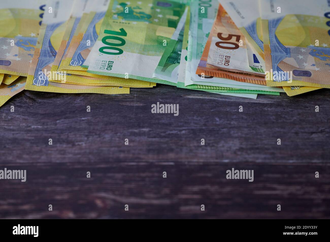 Ci sono diverse banconote in euro sulla parte superiore su sfondo di legno, spazio di copia per qualsiasi testo sotto Foto Stock