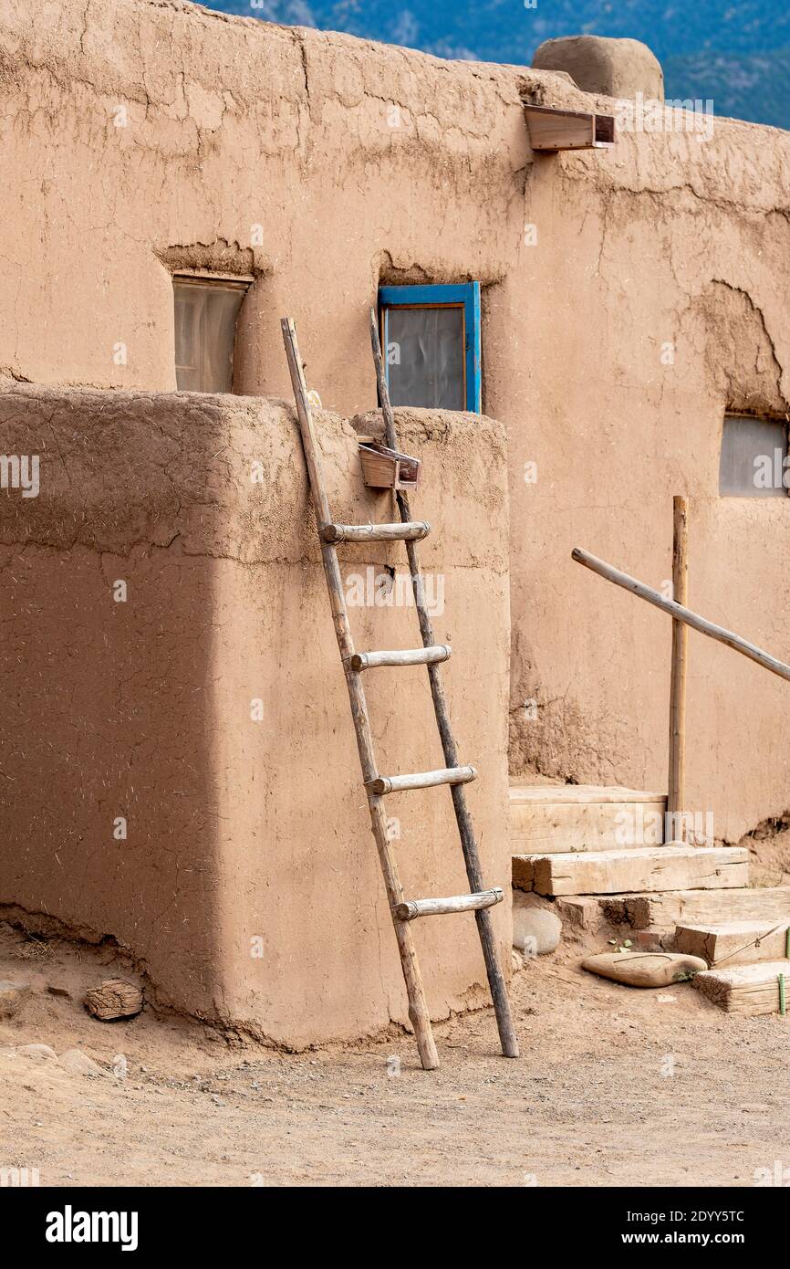 Una scala in legno fatta a mano che pende contro un muro di fango di adobe, nello storico villaggio nativo americano di adobe di Taos Pueblo, New Mexico, USA. UN UNESCO Foto Stock