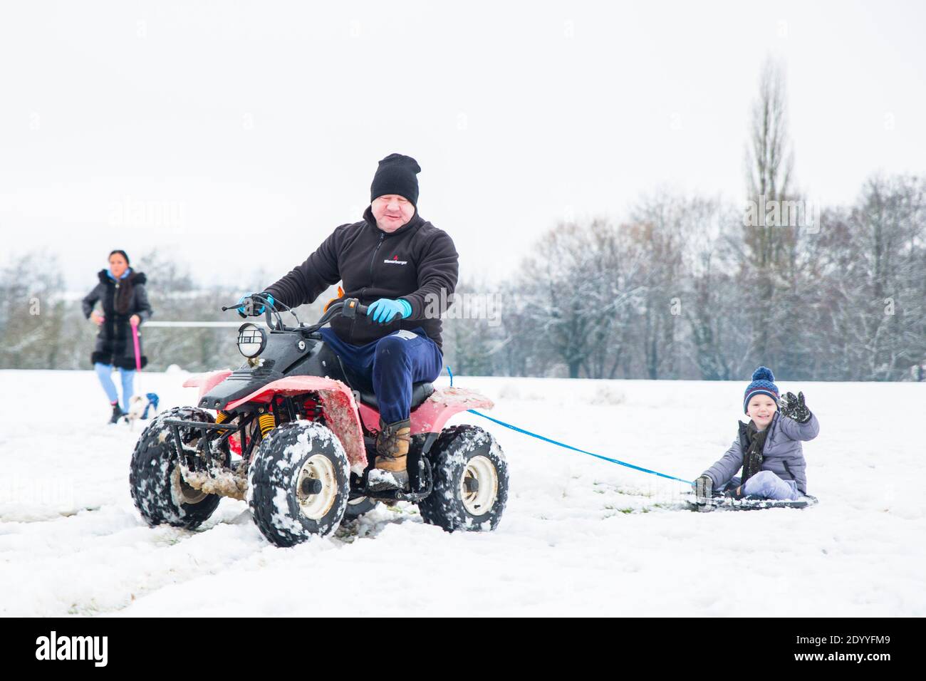 Kidderminster, Regno Unito. 28 dicembre 2020. Tempo nel Regno Unito: Dopo una significativa nevicata in tutto il Worcestershire questa mattina, le famiglie si presentano con idee nuove per intrattenere i loro bambini. Qui abbiamo un ragazzino che viene trainato dietro una moto quad mentre ci si siede a bordo di un coperchio della pattumiera! Credit: Lee Hudson/Alamy Live News Foto Stock