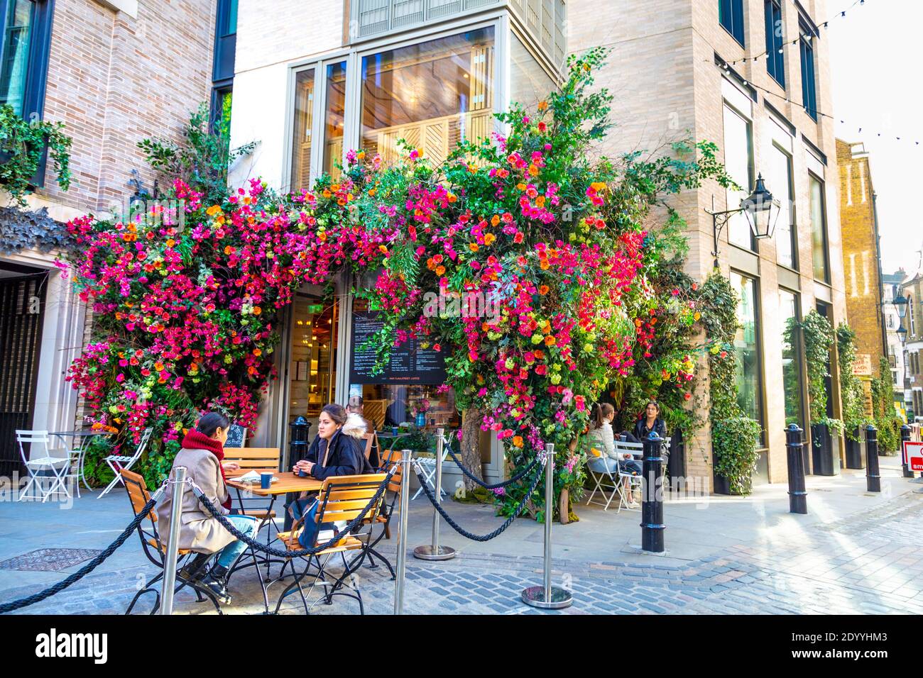 Esterno della Casa del caffè Floral Street decorata con fiori colorati, persone che hanno caffè all'aperto, Giardino Covernt, Londra, Regno Unito Foto Stock