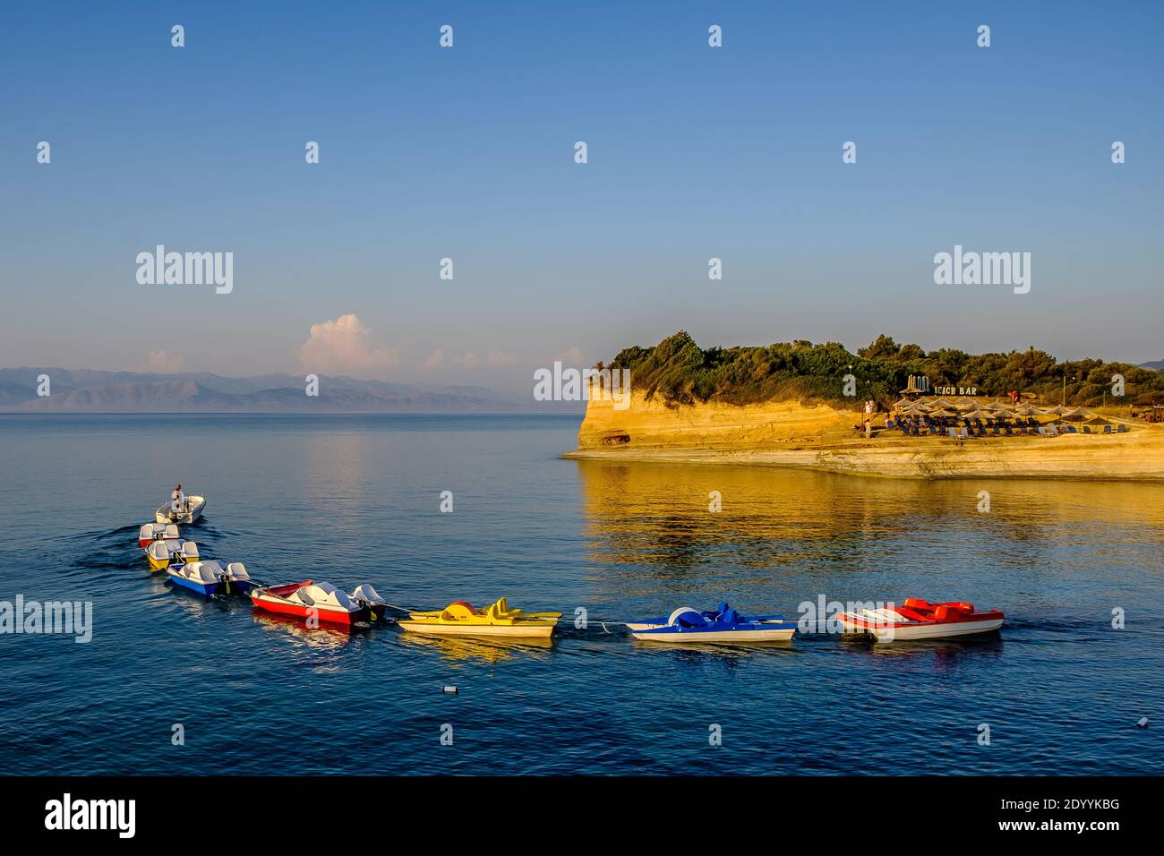 Una piccola barca che tulga una linea di catamarani colorati Foto Stock