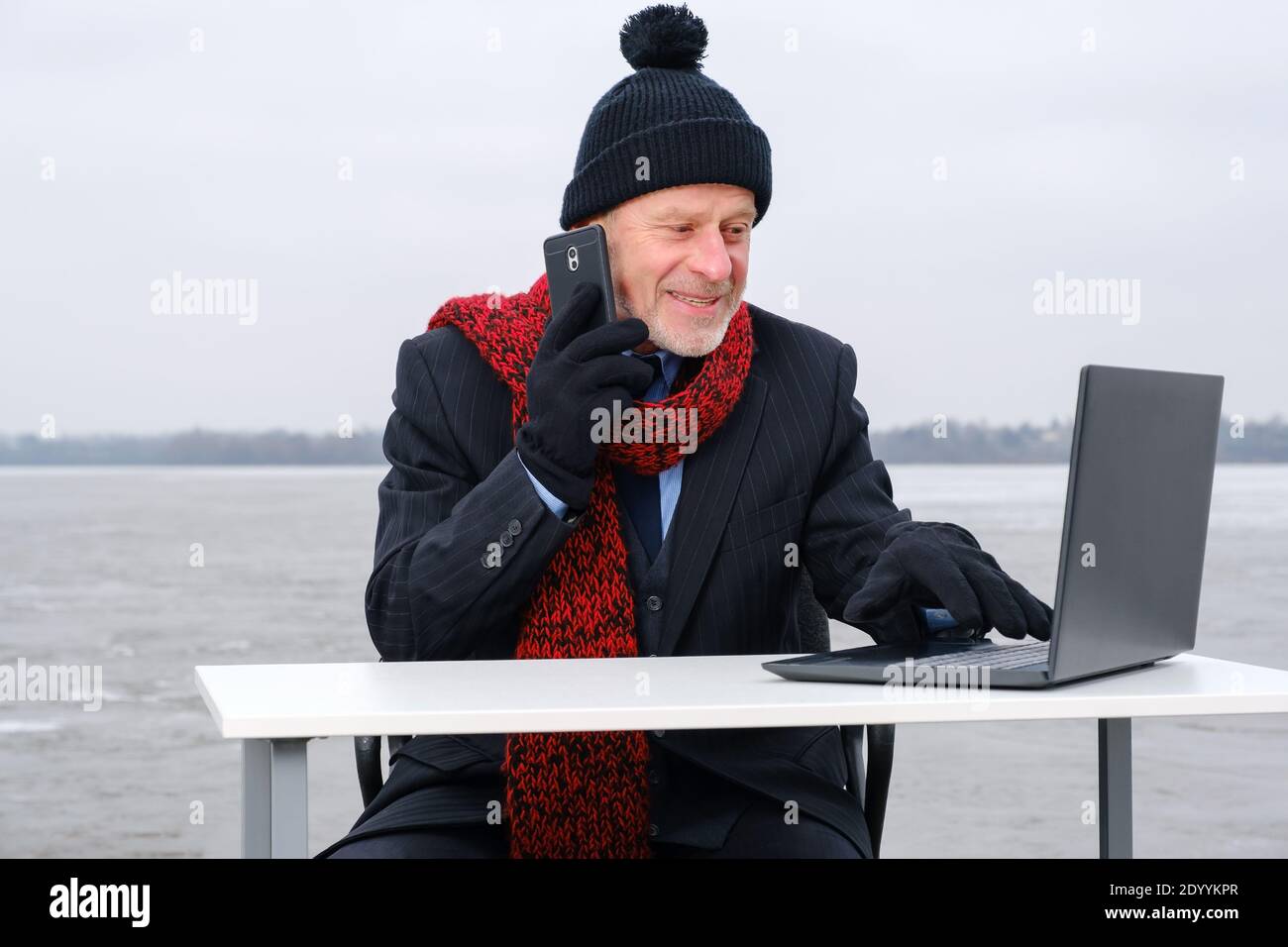 uomo d'affari anziano con la bearded grigia in tuta, sorridente mentre parla sullo smartphone Foto Stock