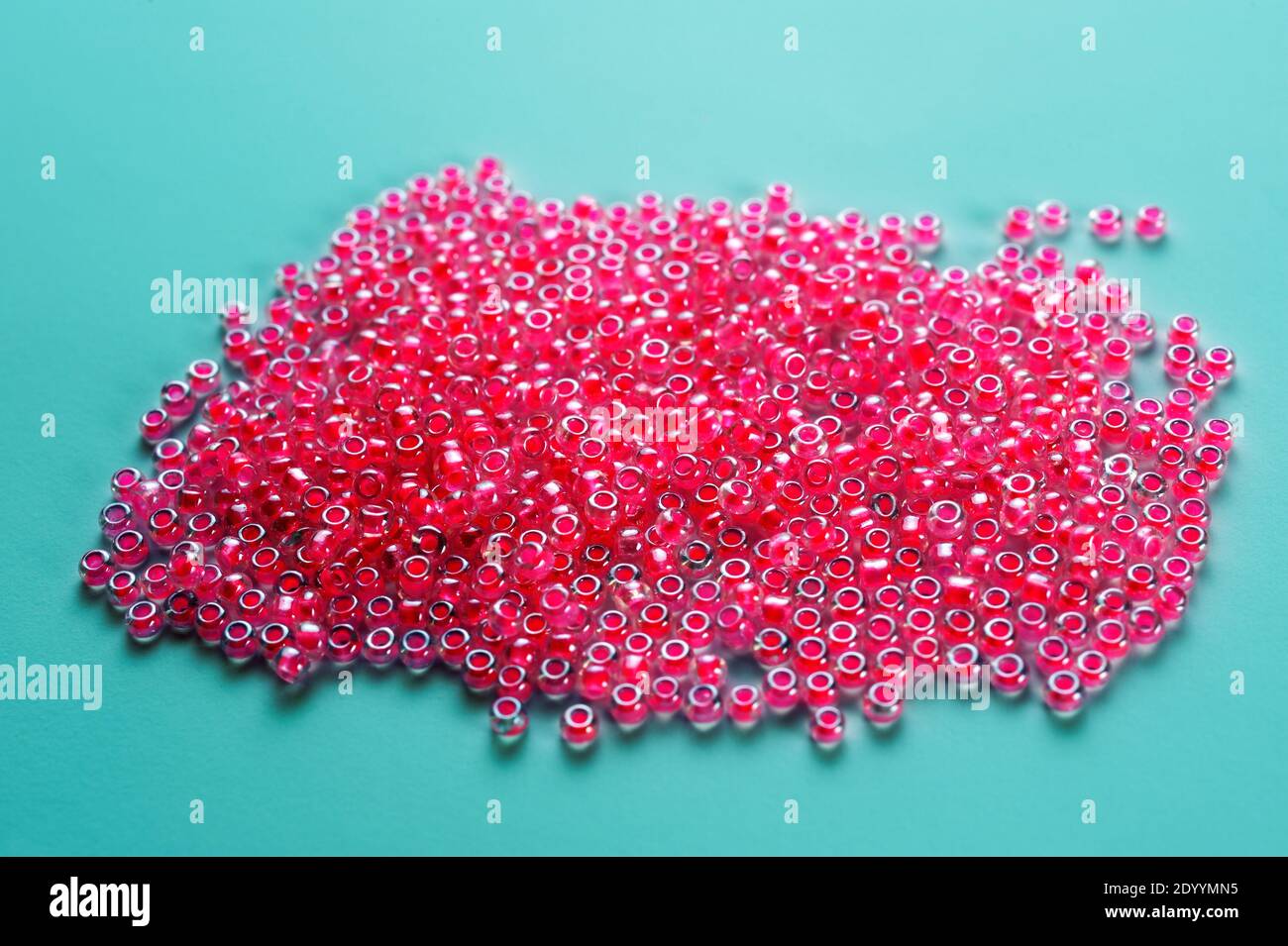 Rosa di piccole sfere di vetro con fori, una sorta di perle artificiali utilizzati per rendere collane di fantasia. Foto Stock