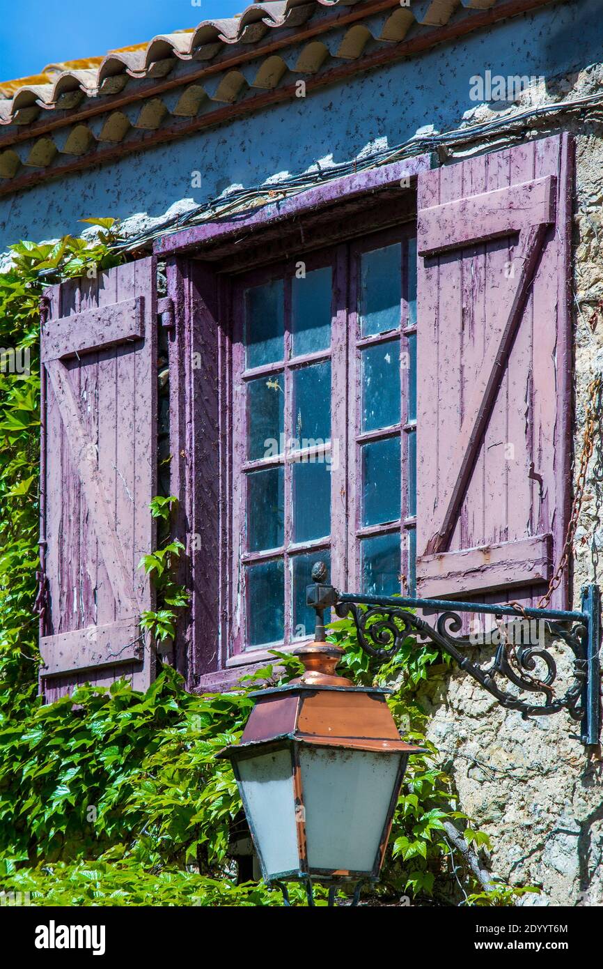 Casa rustica finestra con persiane in legno. ivy e lanterna di strada nel sud della Francia Foto Stock
