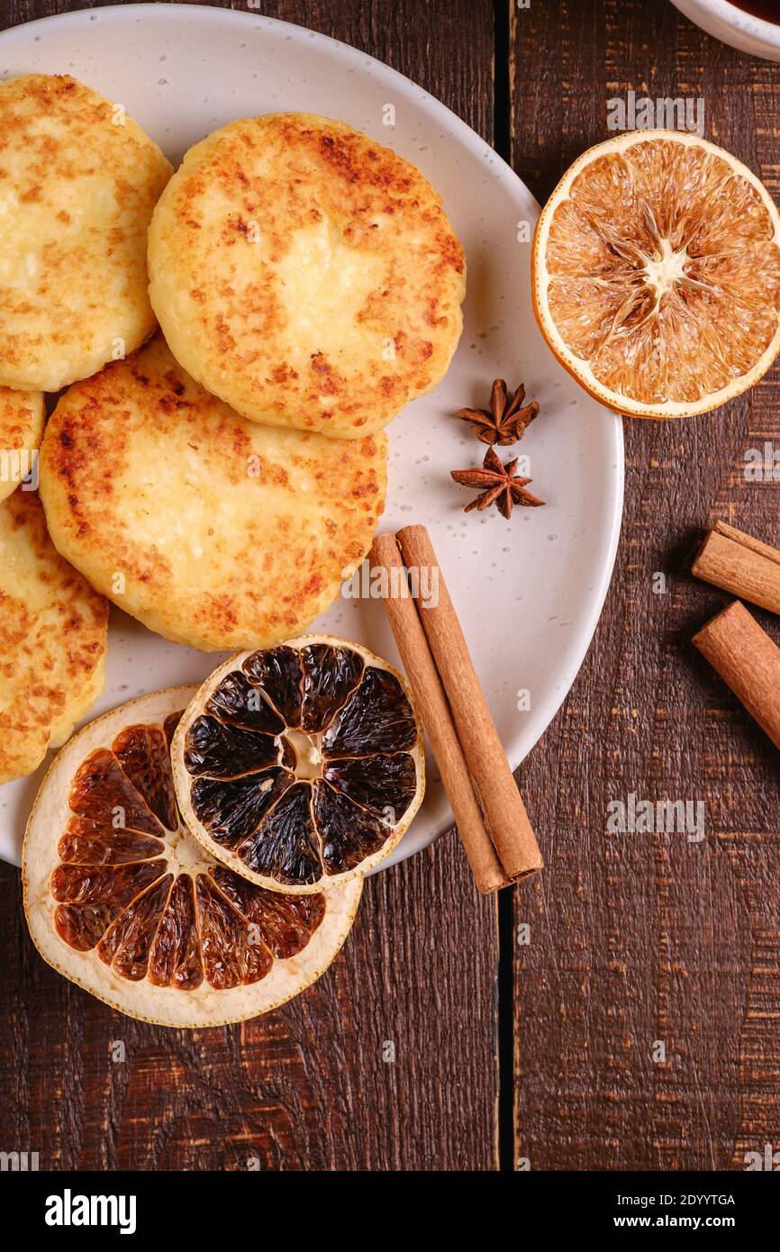 Frittelle di formaggio di cottage, umore di colazione di Natale con anice, cannella e agrumi secchi su sfondo di legno, vista dall'alto Foto Stock