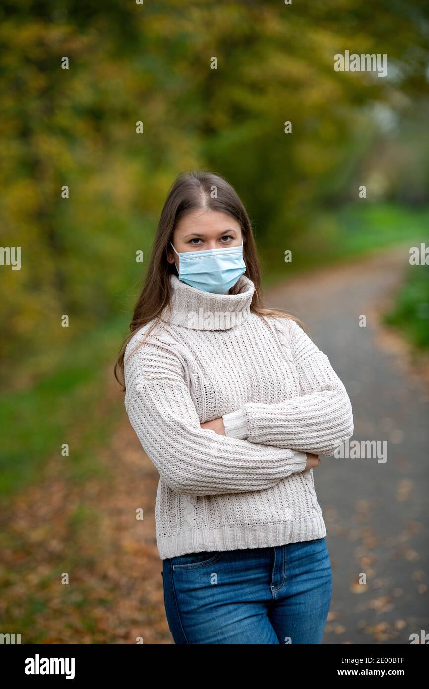 giovane donna nel parco indossa una maschera protettiva durante la pandemia covid-19, stagione autunnale Foto Stock giovane donna nel parco indossa una maschera protettiva durante la pandemia covid-19, stagione autunnale Foto Stock