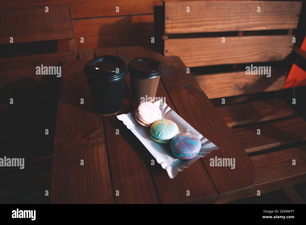 Due tazze monouso con caffè e macaron il tavolo in legno a lato della lontra esterno accogliente atmosfera Foto Stock