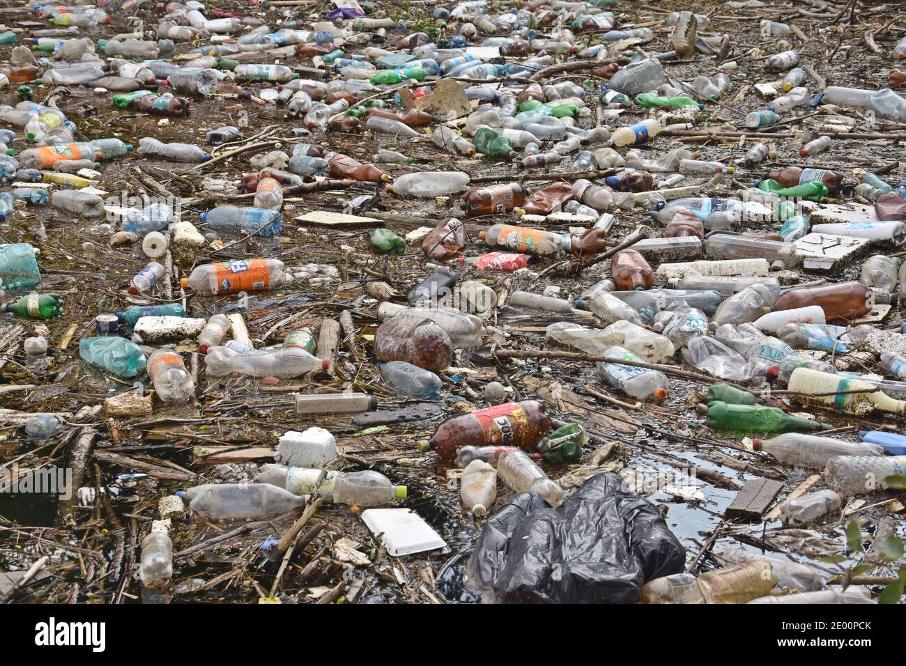 Inquinamento ambientale in montagna. Lago pieno di bottiglie di plastica e rifiuti. Foto Stock