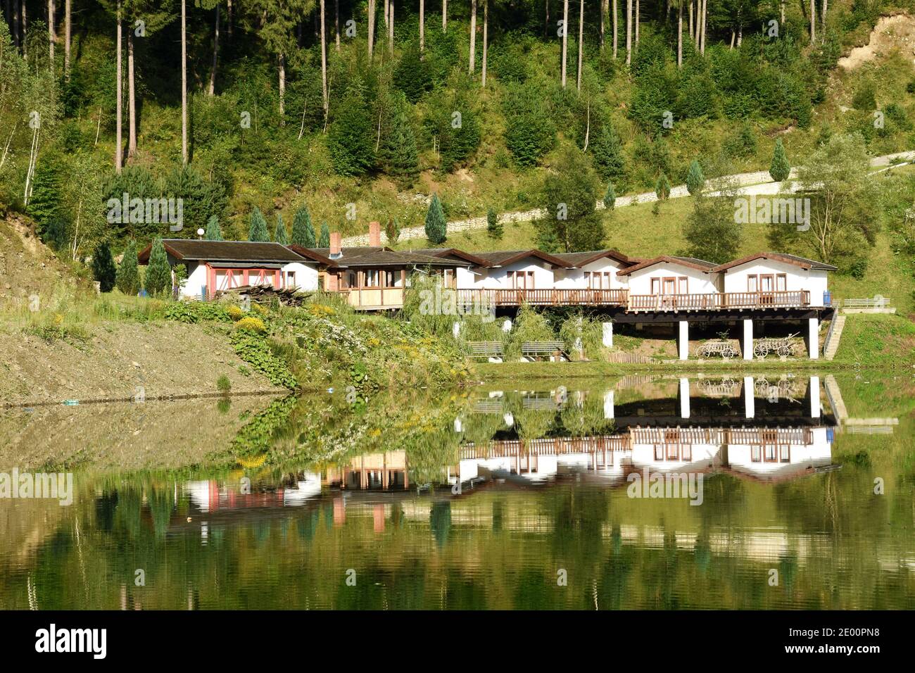 Paesaggio di una pensione e alberi verdi foresta specchiato nel lago. Panorama riflessione in acqua. Foto Stock