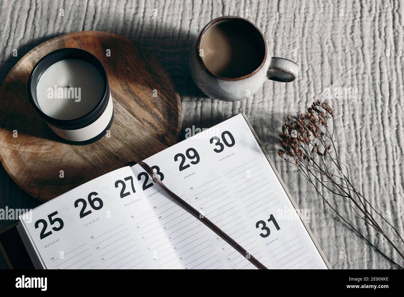 Apri diario, calendario con tazza di caffè. Candela e pianta asciutta su fondo di stoffa da tavolo beige. Piani futuri, risultati per il nuovo anno 2021. Ora Foto Stock