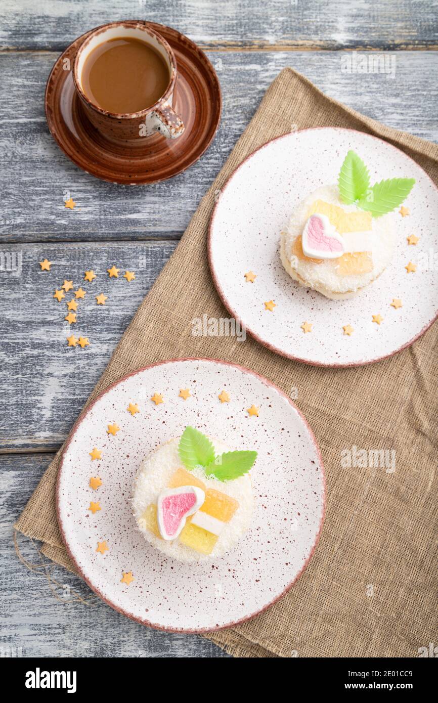 Torta decorata con latte e crema di cocco con tazza di caffè su fondo grigio in legno e tessuto di lino. Vista dall'alto, piatto, primo piano. Foto Stock