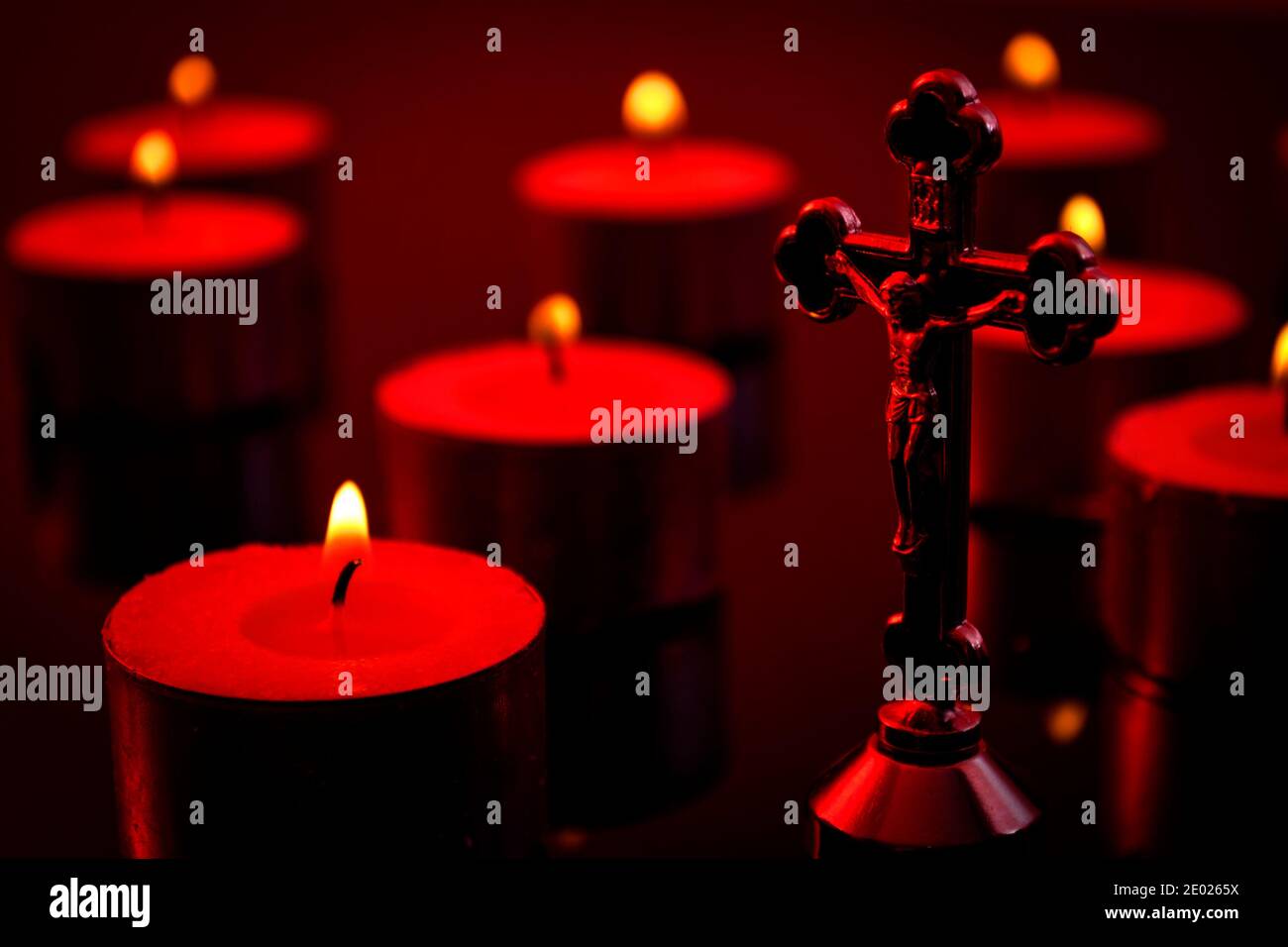 Concetto di cristianità, fede e credenza religiosa con una scena a lume di candela di un crocifisso che rappresenta Gesù Cristo sulla croce e una candela illuminata sfocata Foto Stock