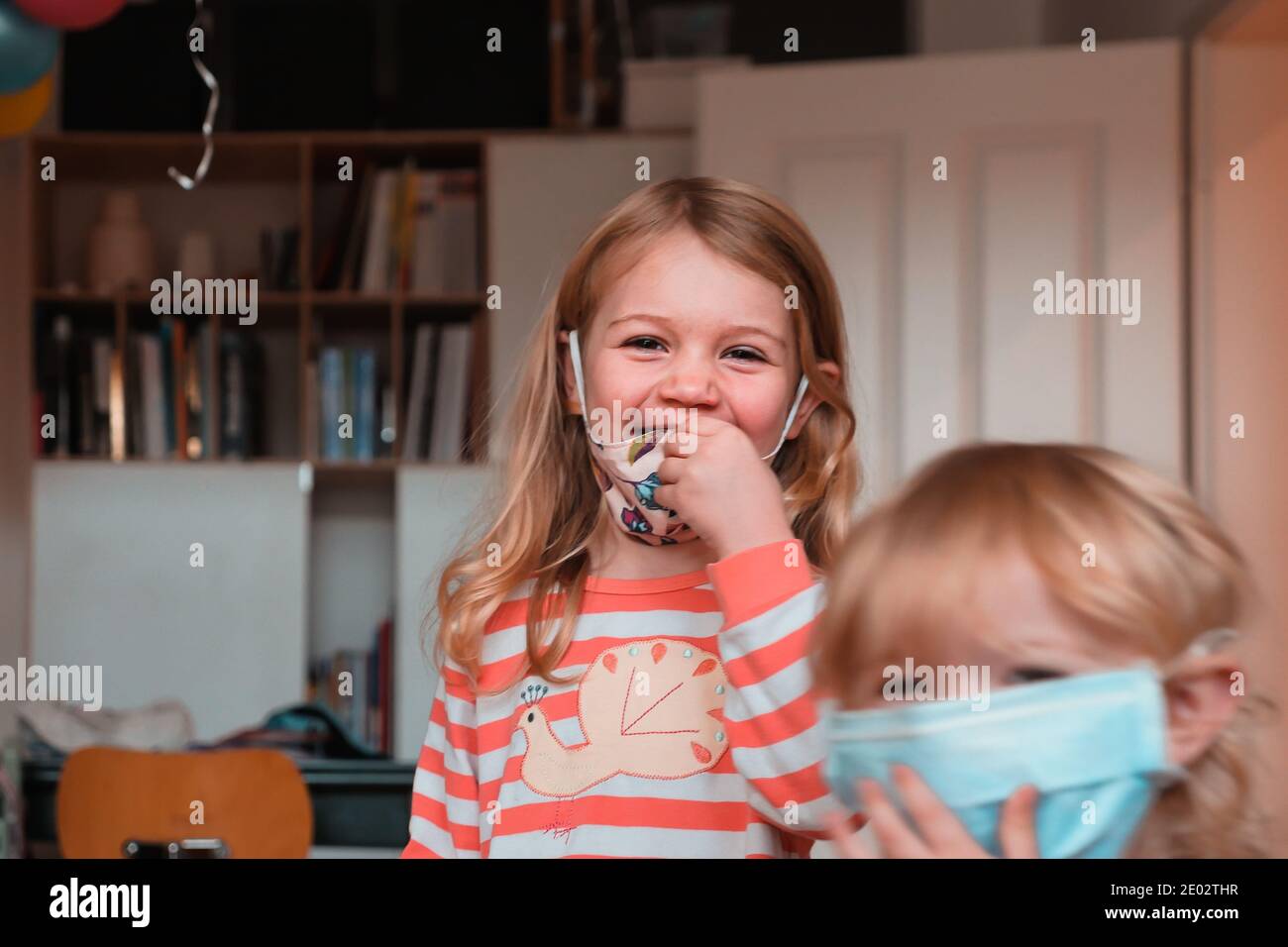 Sorelle che si divertono e sorridono con maschere facciali a casa. Scatto medio. Foto Stock