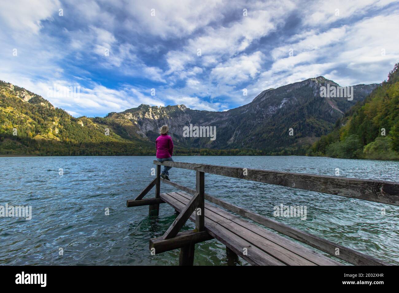 Giovane ragazza che si riposa sul lago di montagna, Austria. Donna che viaggia godendo di vista delle Alpi. Wanderlust concetto di libertà di viaggio. Avventura estiva vacanza Foto Stock