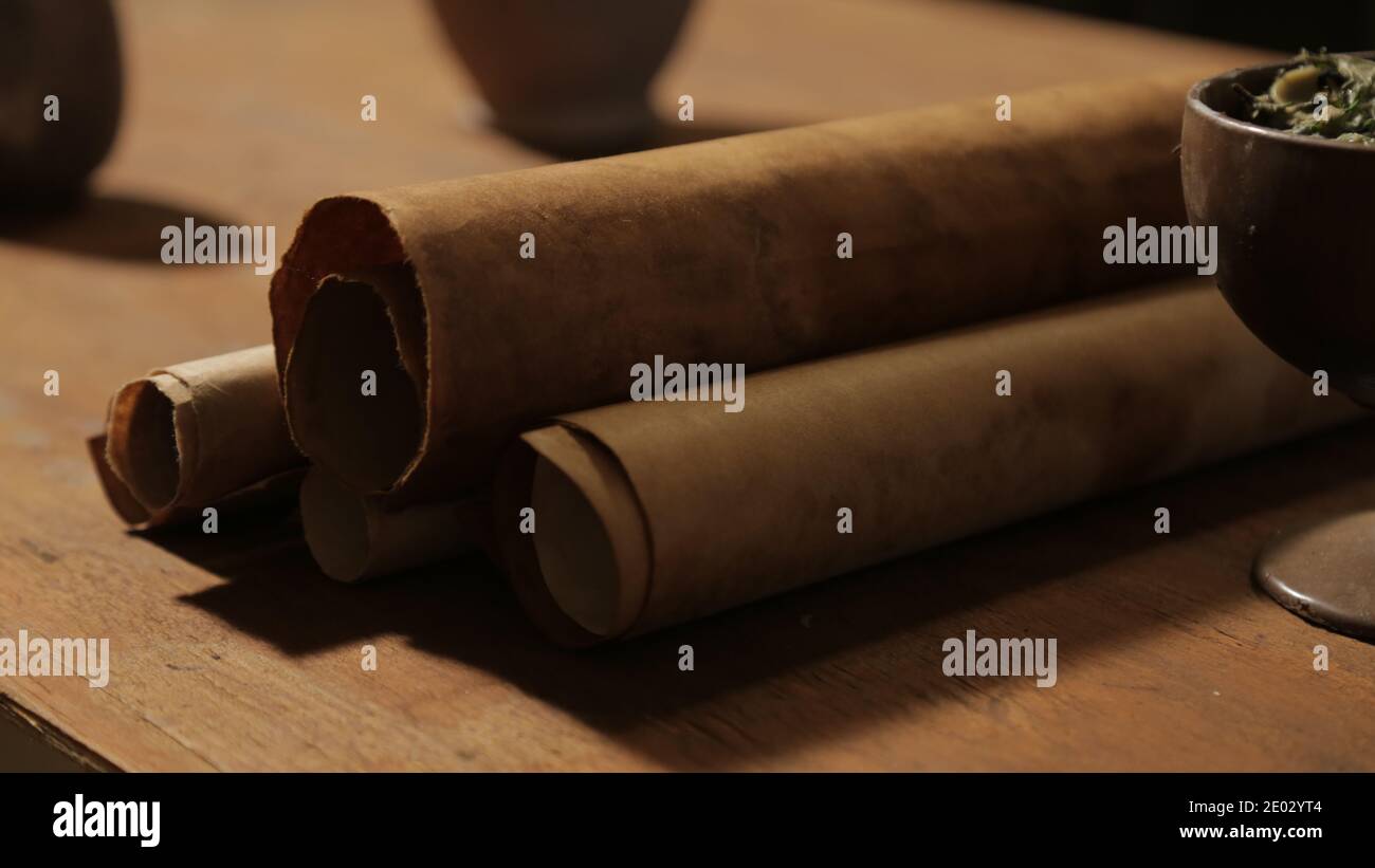 Scena biblica: Un tavolo da pranzo in legno con le Scritture scorre. Primo piano di rotoli di carta vecchia, tazza con cibo. Foto Stock