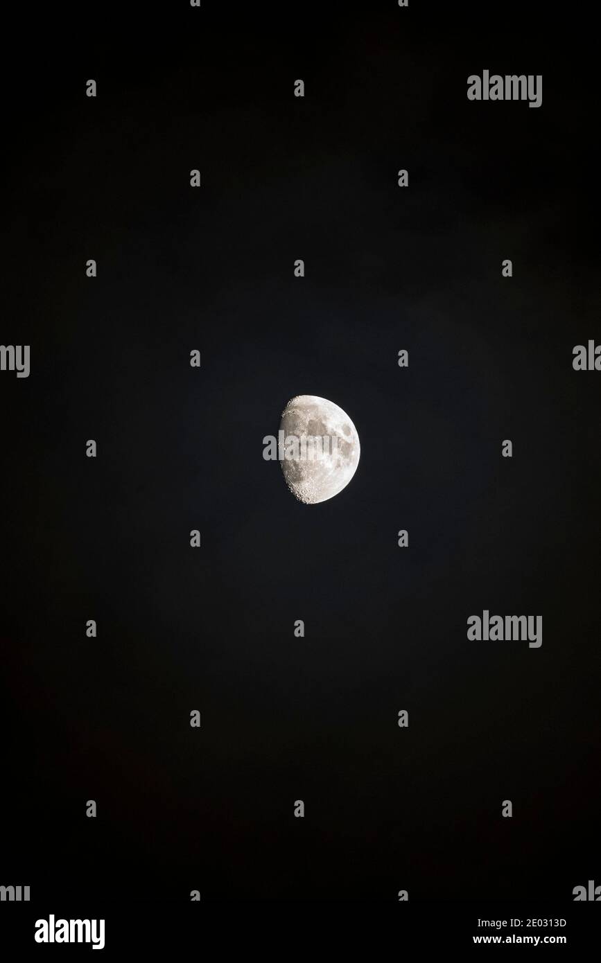 Una luna gibbosa cerosa (tra la metà e i tre quarti) in un cielo notturno scuro. Formato verticale Foto Stock