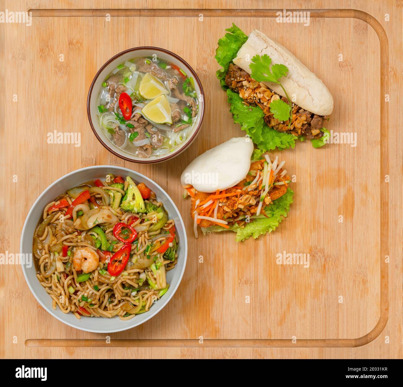 Cibo asiatico take away varietà su tavolo di legno. Pho zuppa, bao mun, mare cibo noodles piatti consegna a domicilio Foto Stock