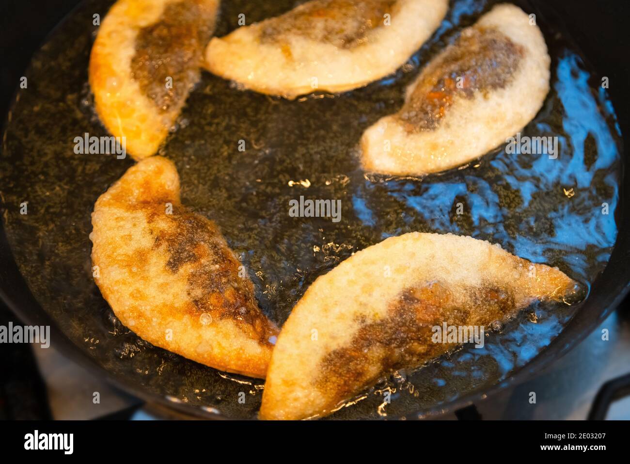 Gnocchi di Gyoza con farcitura di funghi in padella calda. Gnocchi dorati croccanti che cucinano in olio. Foto Stock