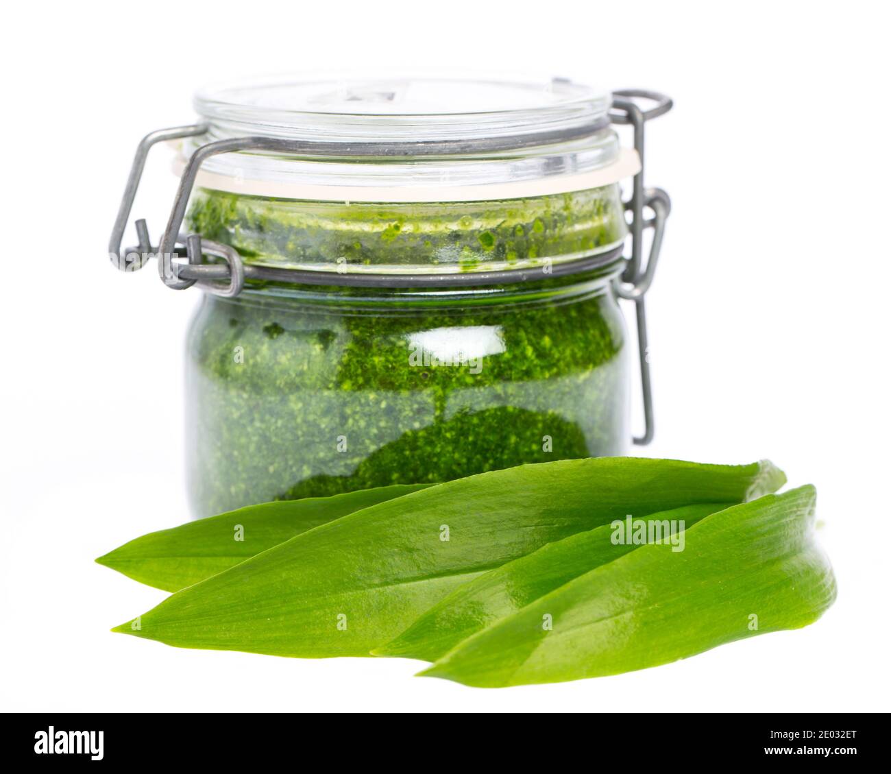 Foglie di aglio selvatico davanti ad un bicchiere con selvatico pesto di aglio Foto Stock