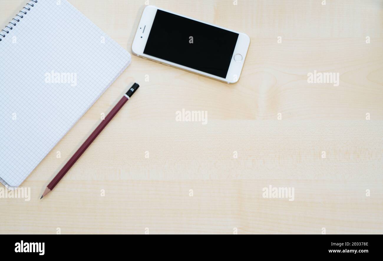 Vista dall'alto dello spazio di lavoro, del tavolo da lavoro con smartphone, notebook, penna. Lavoro mobile. Disposizione piatta Foto Stock
