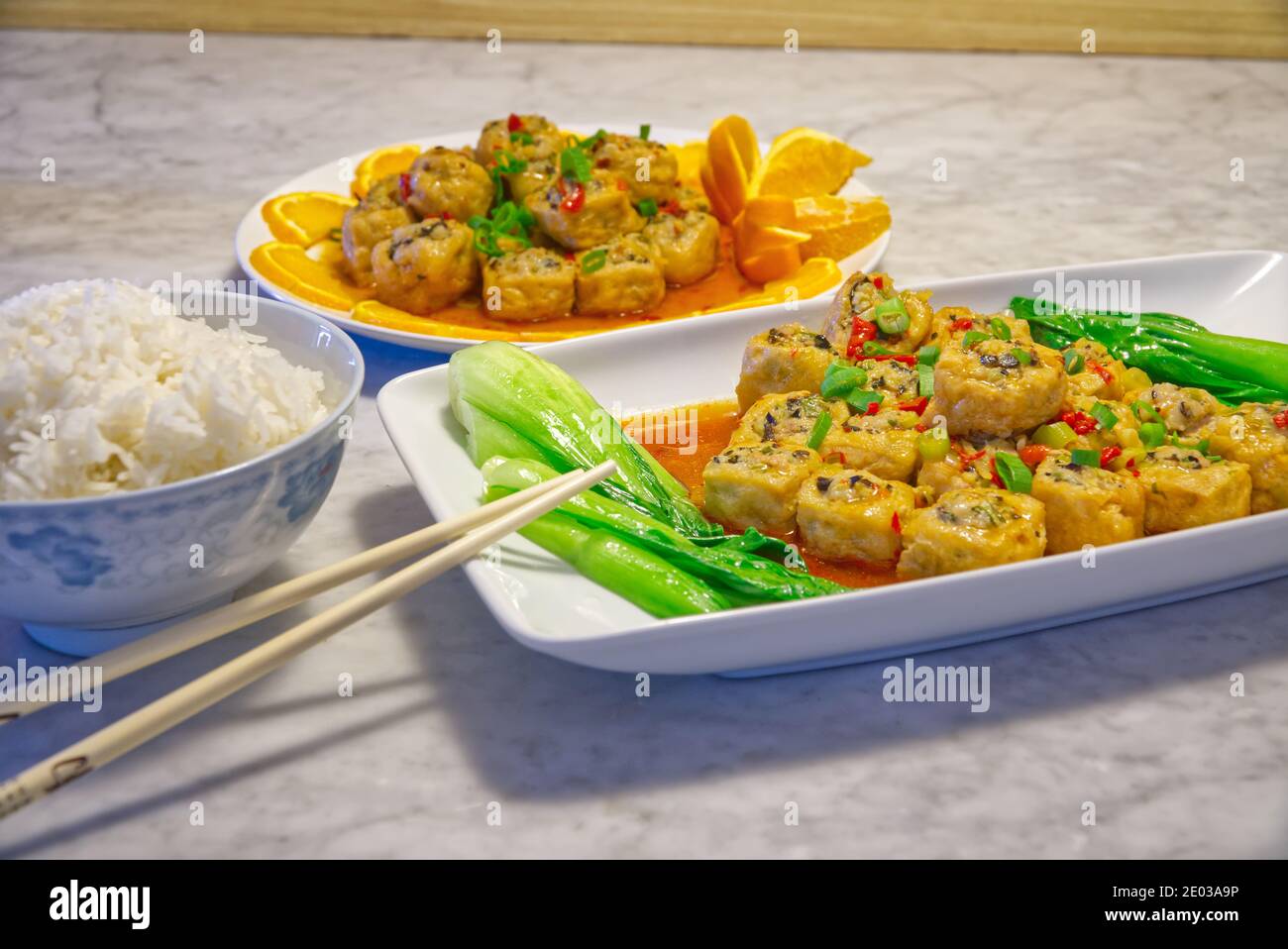 Mescolare i cubetti di tofu ripieni fritti con verdure, riso bianco, chopsticks e piatti. Mangiare sano Foto Stock
