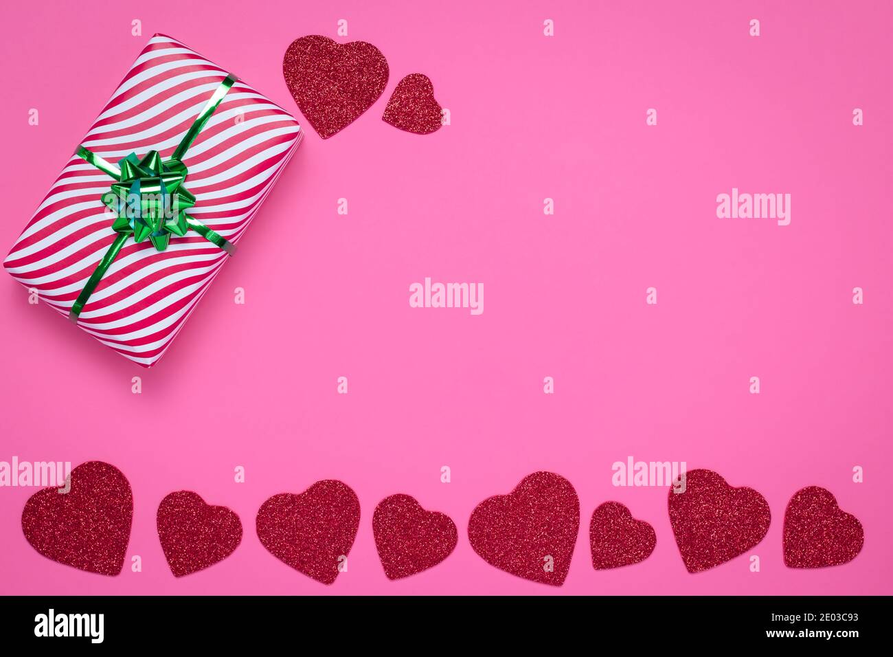 Cornice rosa con cuori. Concetto di giorno e amore di San Valentino. Scheda romantica con disegno d'arte e spazio di copia per il testo. Modello carino con una confezione regalo a righe Foto Stock