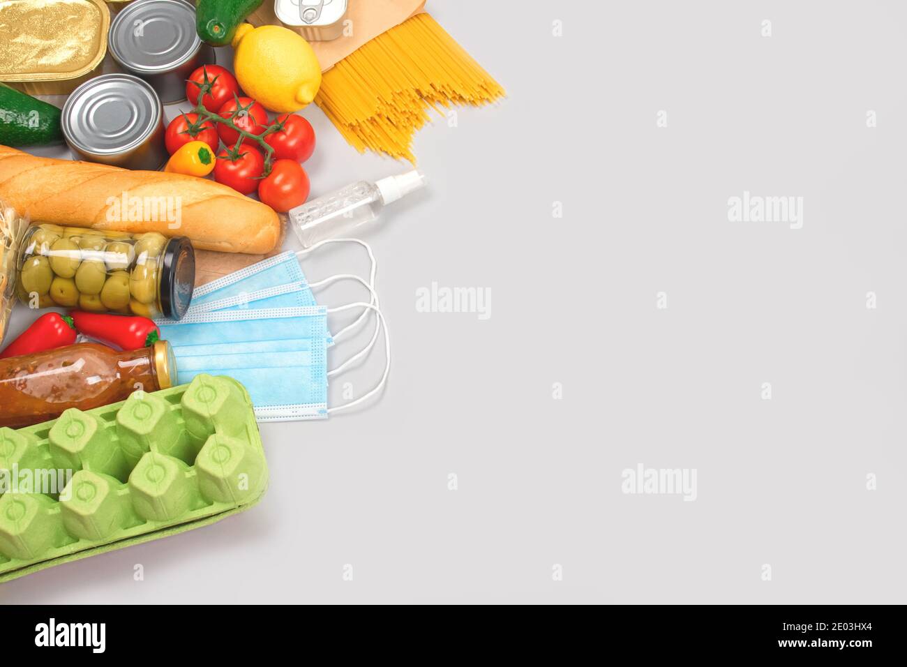 Composizione piatta con donazioni di cibo e medicine su sfondo grigio con copyspace - pasta, verdure fresche, cibo in scatola, baguette, olio da cucina Foto Stock
