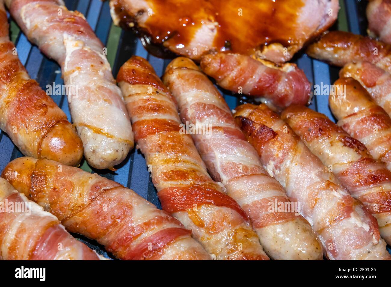 Piatti tradizionali di Natale: Maiali in coperte, salsicce avvolte in pancetta, cotti, posati su un piatto Foto Stock