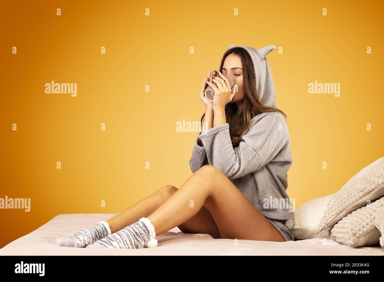 Bella giovane donna che indossa pigiami kigurumi, con una bevanda calda Foto Stock
