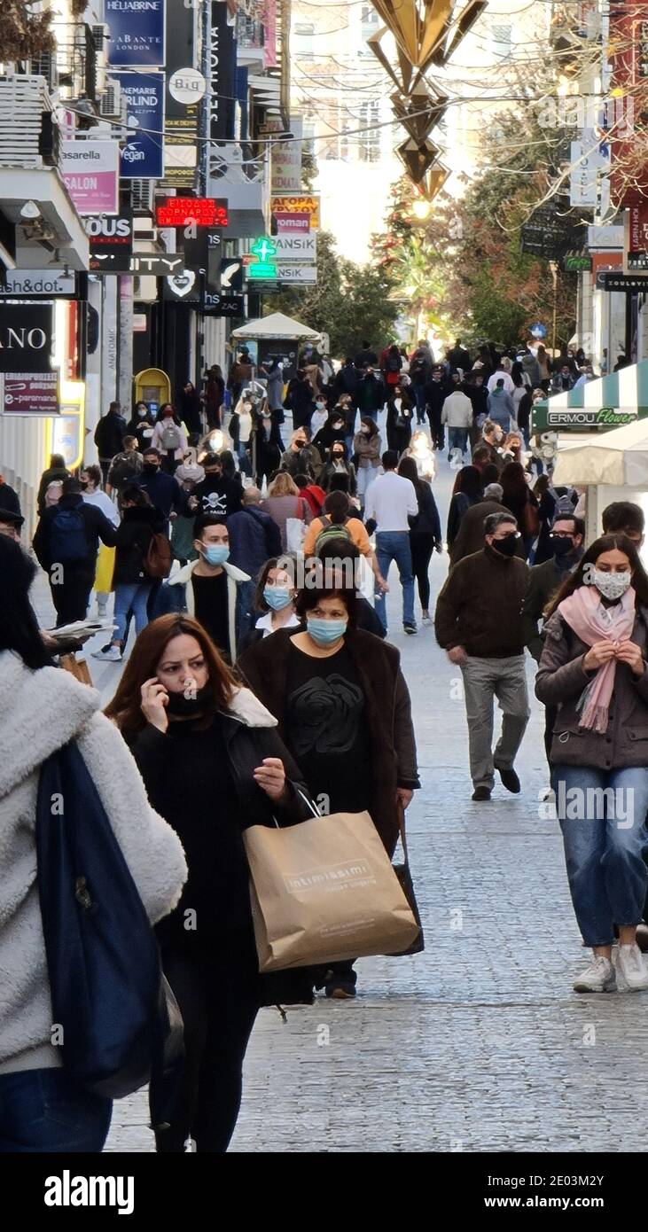 Folla di persone con maschere in una strada commerciale ad Atene, Grecia Foto Stock