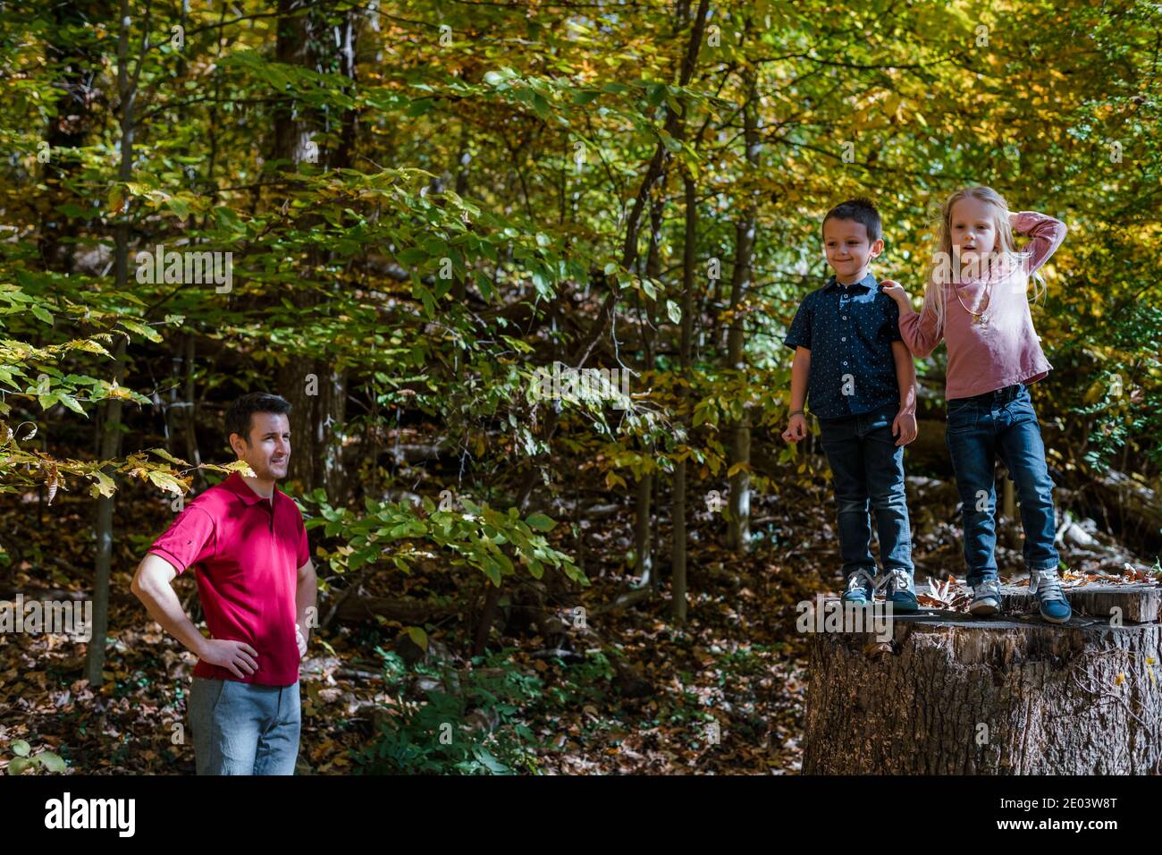 I bambini giocano nella foresta mentre il papà guarda Foto Stock