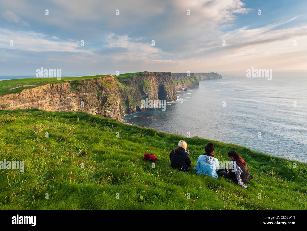 Scogliere fuori Moher Clare County Irlanda Europa tre ragazze seduta sull'erba godendo la vista delle scogliere in una giornata estiva Foto Stock