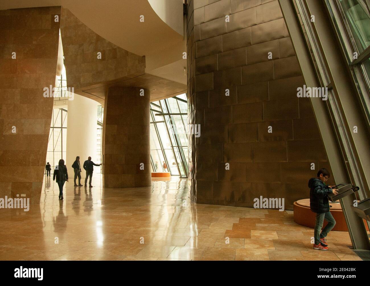 Lobby in un'ondata di luce nell'enorme interno del Museo Guggenheim, silhouette dei visitatori, schermo informativo per i bambini. Foto Stock