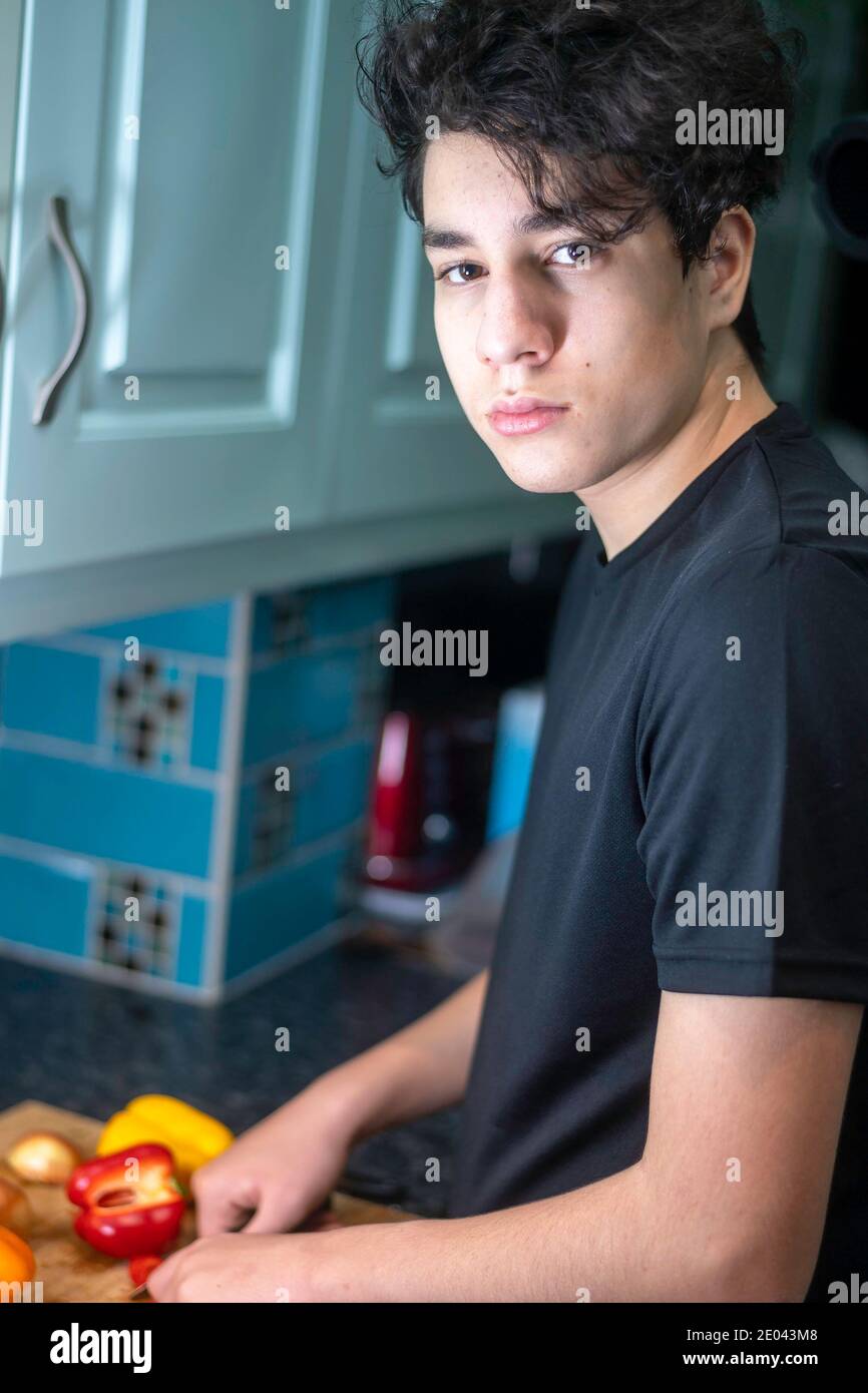 Teenage misto corsa ragazzo preparatori verdure in cucina Foto Stock