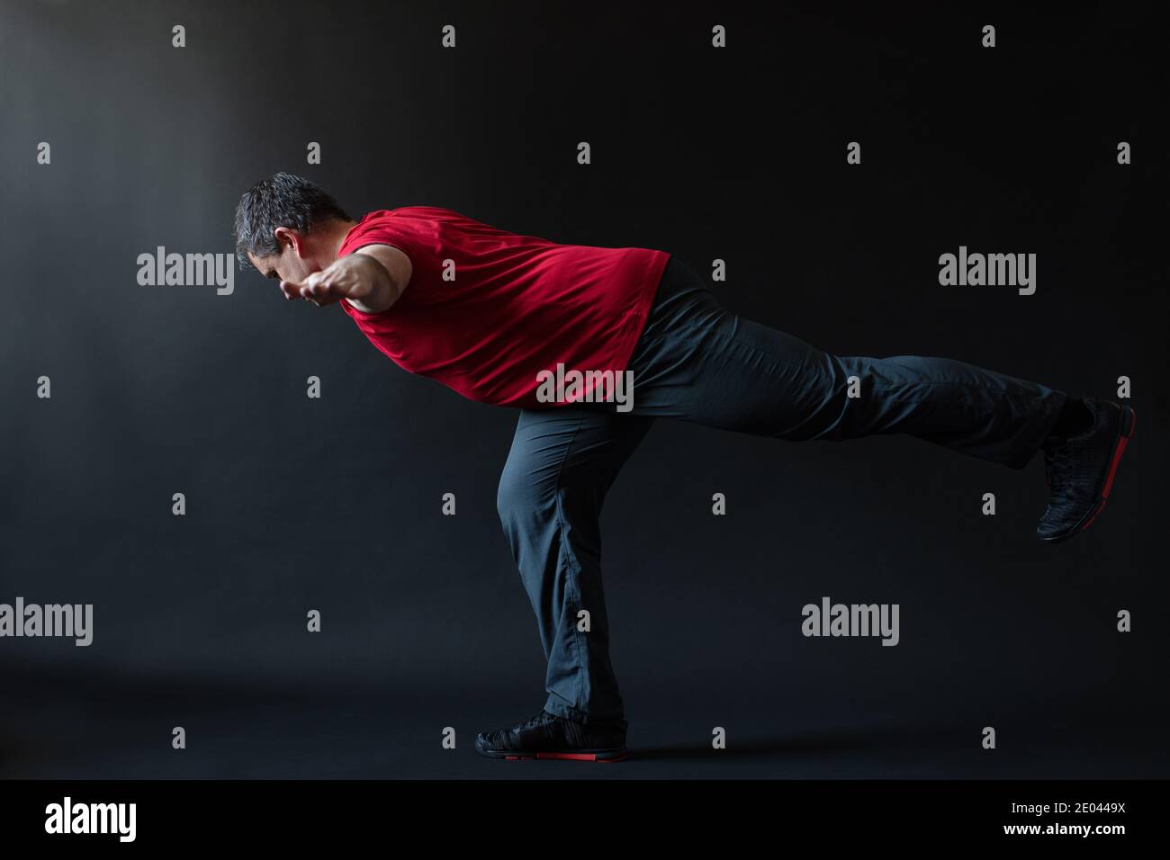Ritratto di un atleta maschile pensieroso di età compresa tra 35 e 45 anni in abito sportivo rosso su sfondo nero. Foto Stock