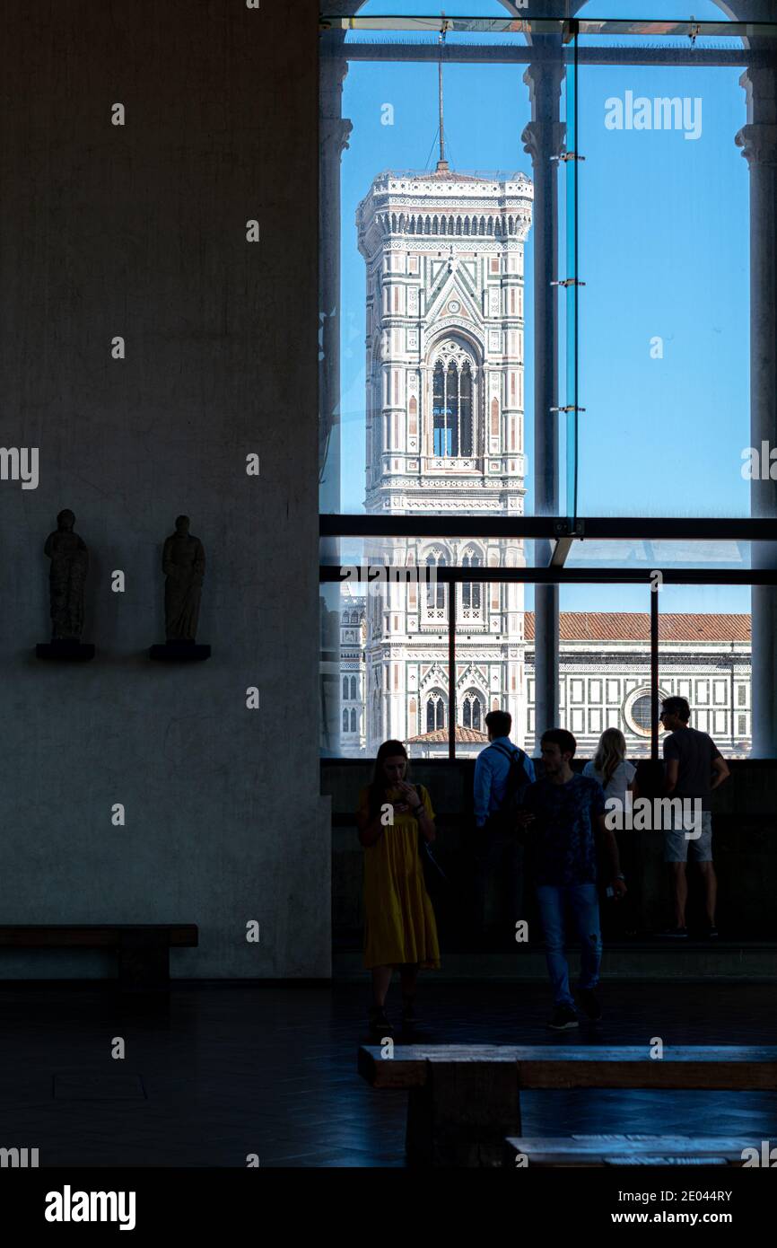 Turisti che guardano la vista del Campanile di Giotto a Firenze attraverso le finestre dell'Orsanmichele, Italia Foto Stock