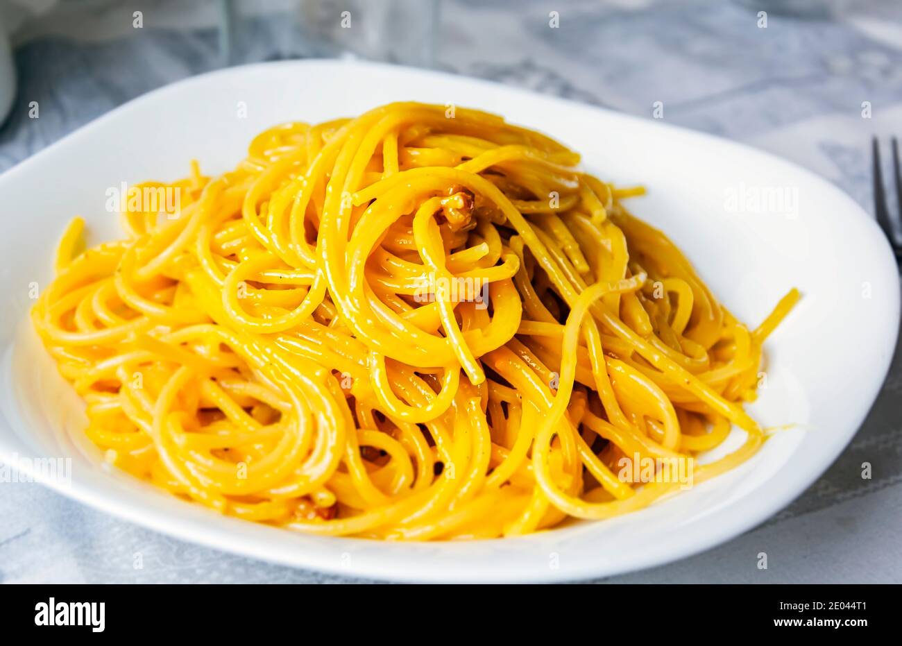 Ampia porzione di spaghetti carbonara in un piatto bianco. Cucina italiana. Cucina tipica romana. Foto Stock