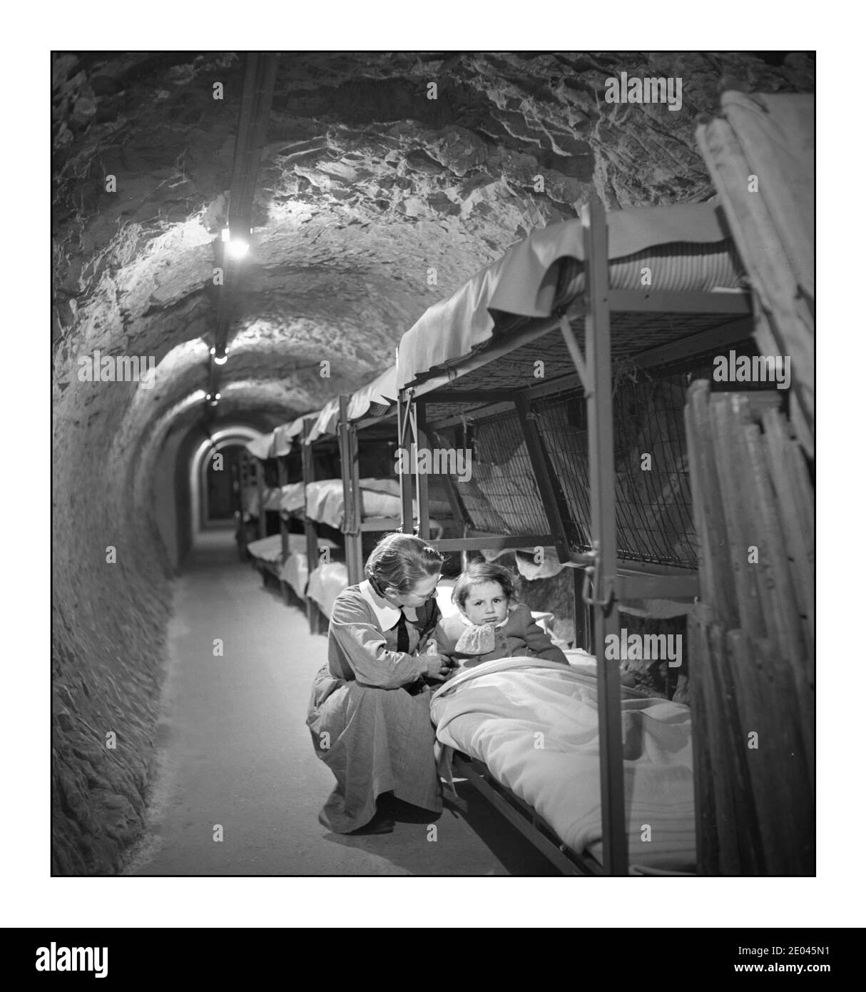 WW2 London Blitz Woman si inginocchiò accanto al letto del bambino, in un tunnel aereo sotterraneo durante il bombardamento di Londra durante la seconda guerra mondiale Frissell, toni, 1907-1988, fotografo [1945 gennaio] – Guerra Mondiale, 1939-1945--Difesa civile--Inghilterra--Londra-1940-1950 - Tunnels--Inghilterra--Londra-1940-1950 Air raid shelters--Inghilterra--Londra-1940-1950 Foto Stock