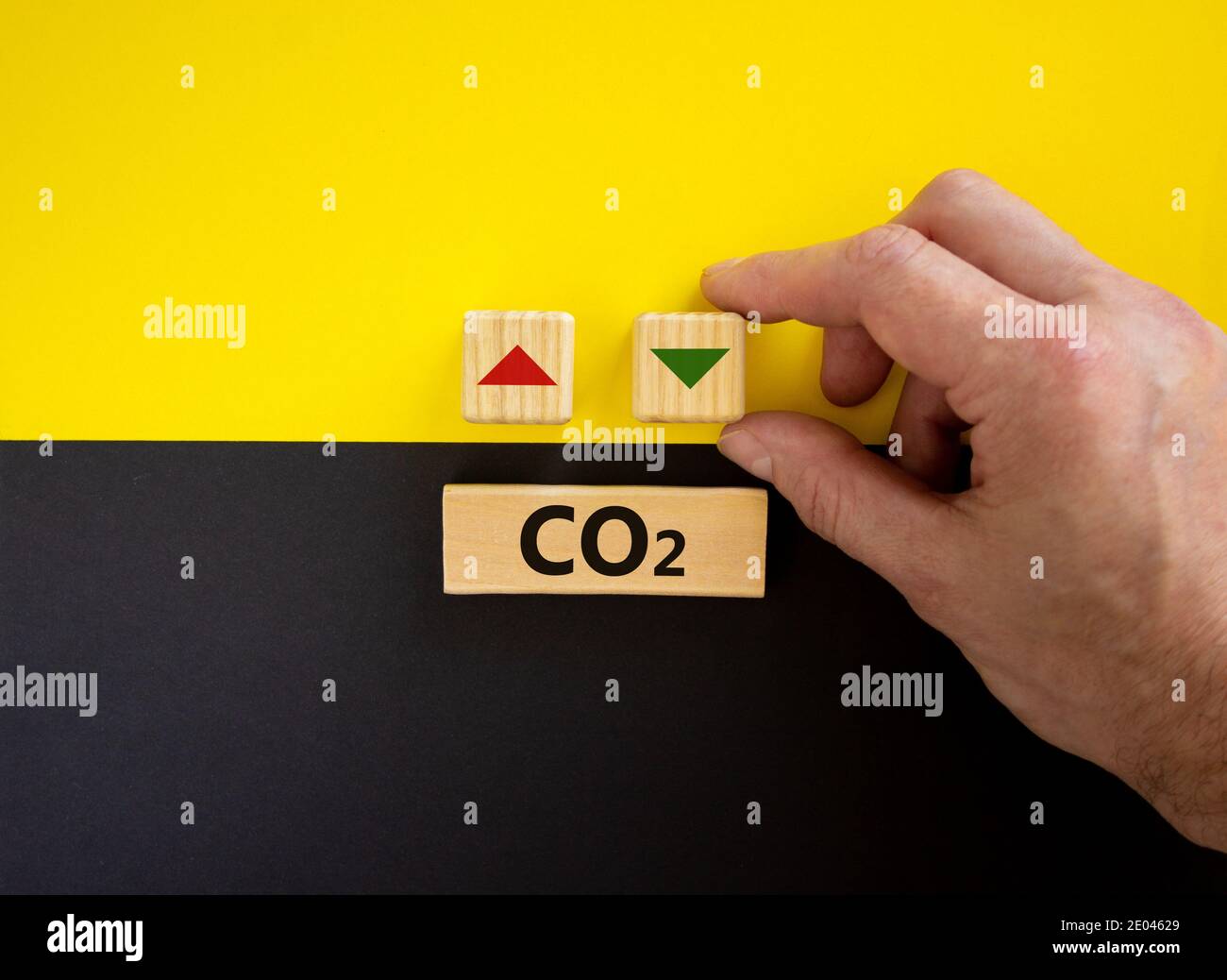 Simbolo modifiche CO2. Parole concettuali 'CO2' su cubi e blocchi su uno splendido sfondo giallo e nero. La mano maschile cambia la direzione di una freccia sy Foto Stock