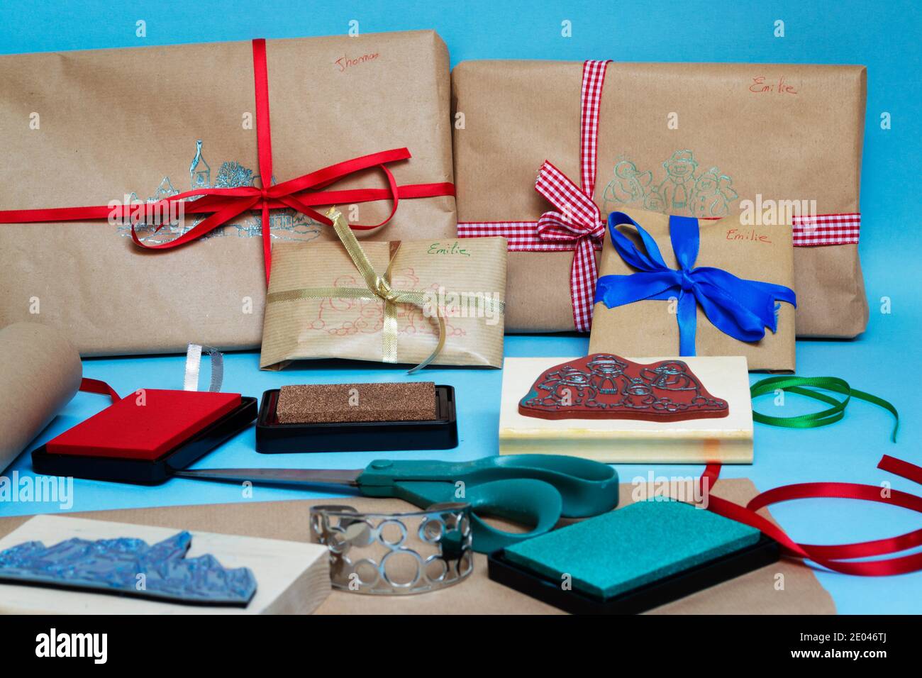 Confezionare i regali di Natale in modo ecologico con carta marrone, nastri e francobolli Foto Stock